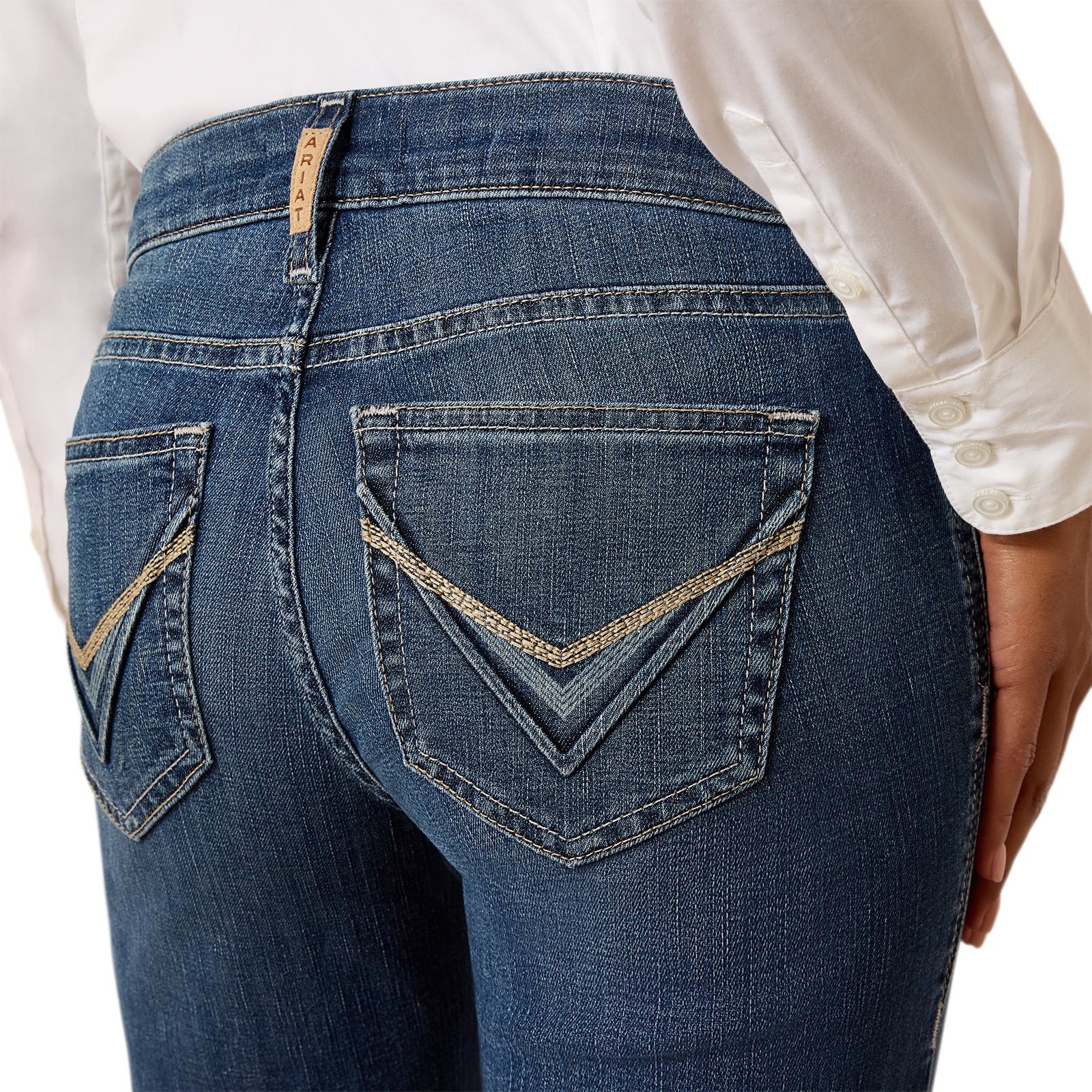 Close-up of blue jeans with a white shirt worn by a person on a white background