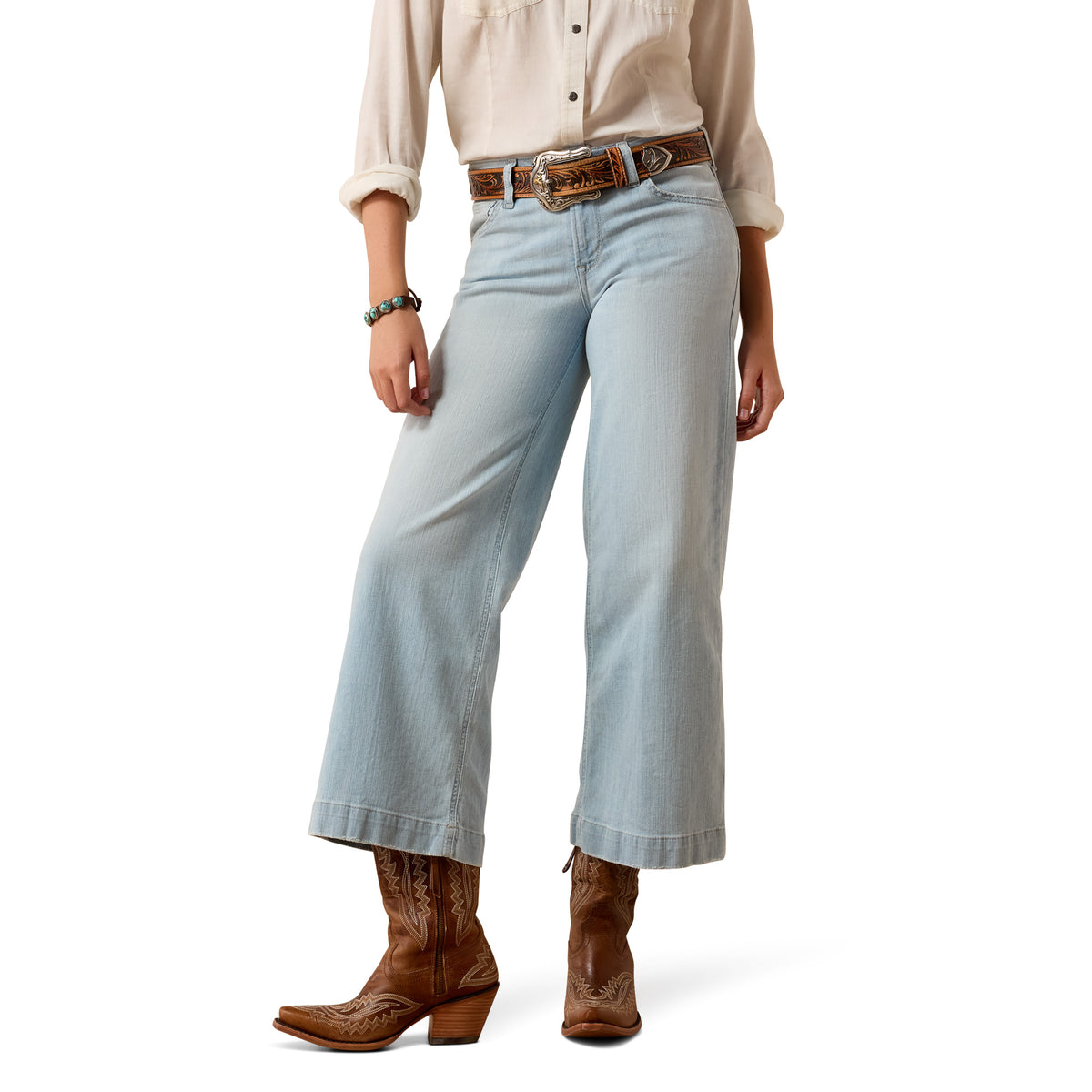 Person wearing light blue jeans and brown cowboy boots on a white background