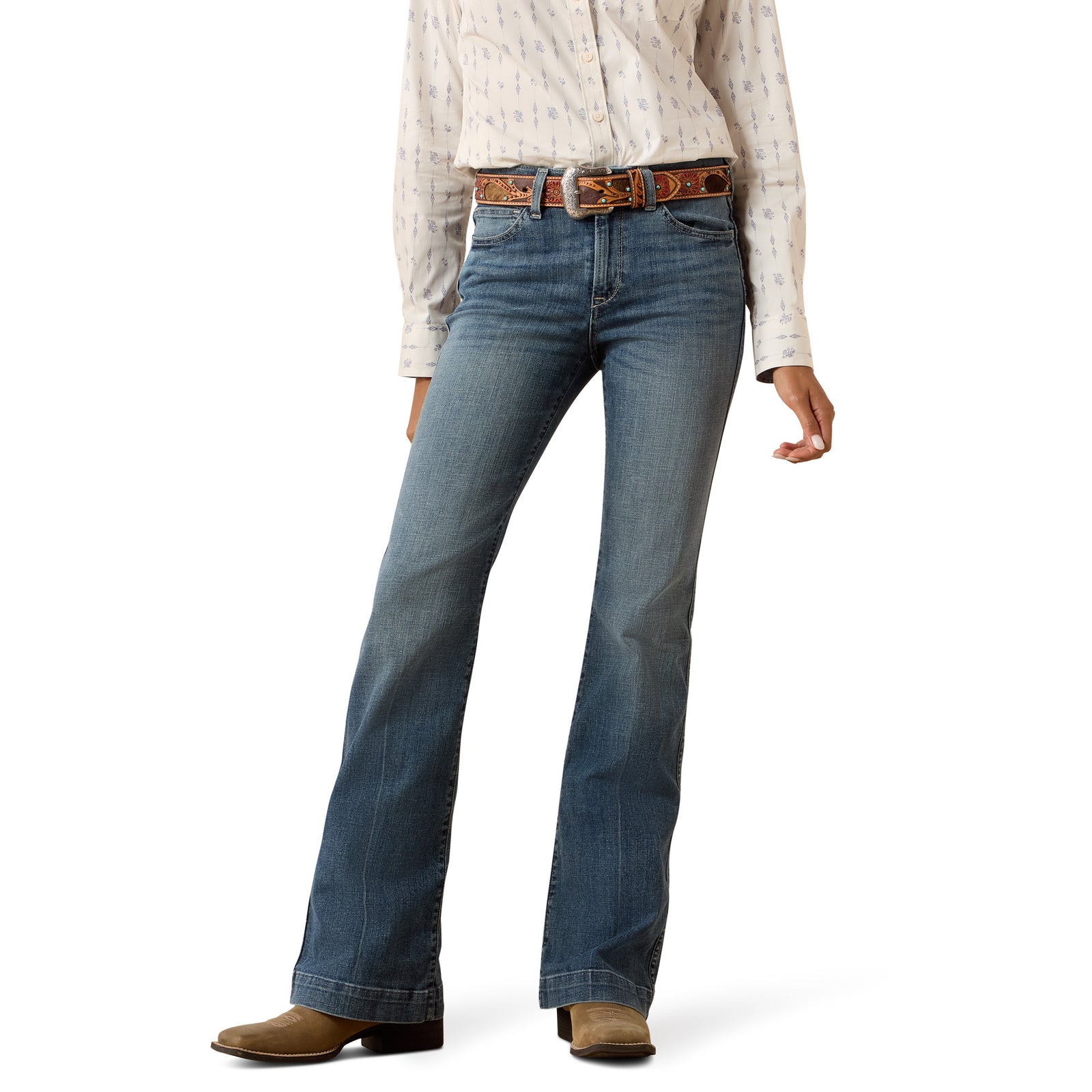 Person wearing blue jeans and a patterned shirt on a white background