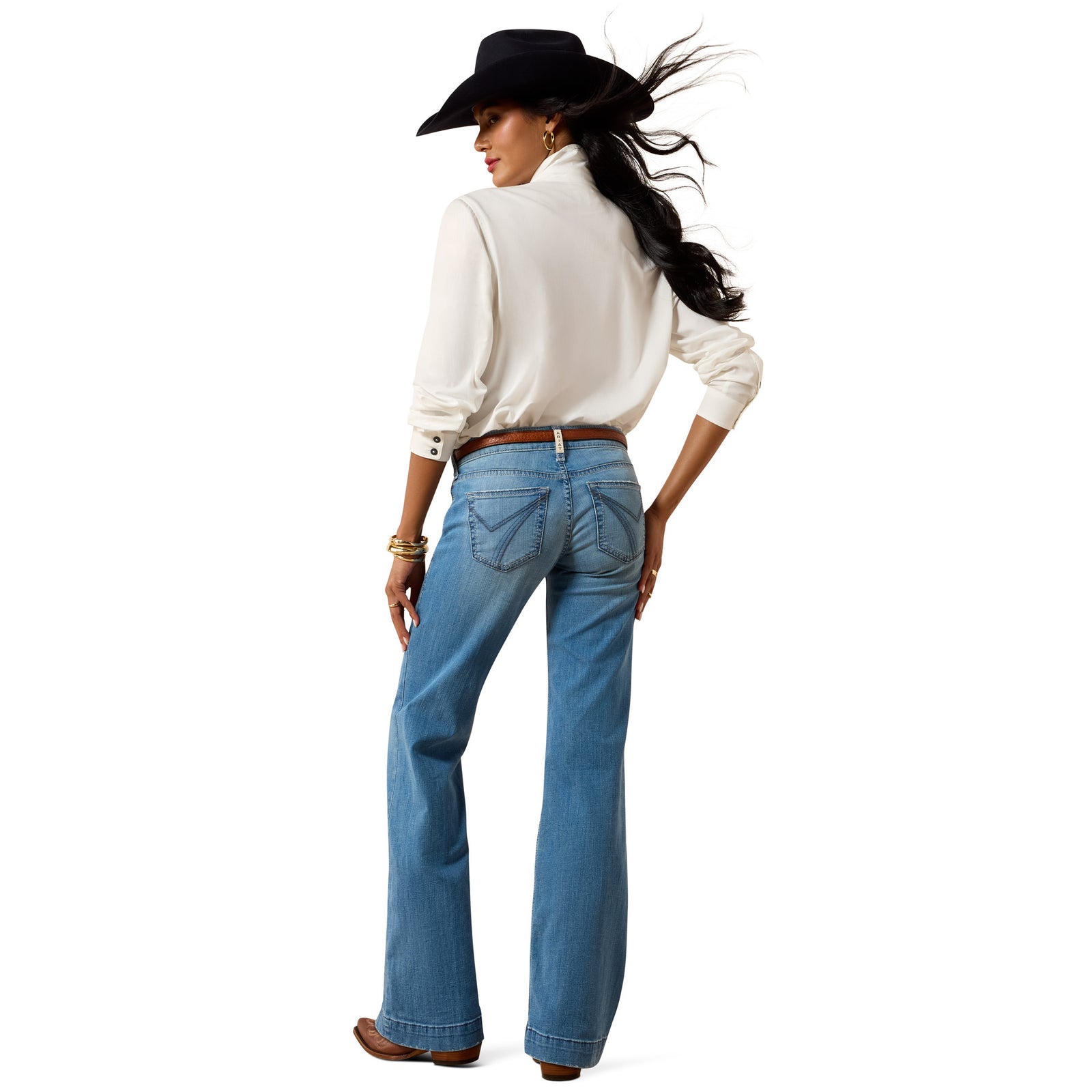 Woman wearing a white blouse, blue jeans, and a black cowboy hat on a white background