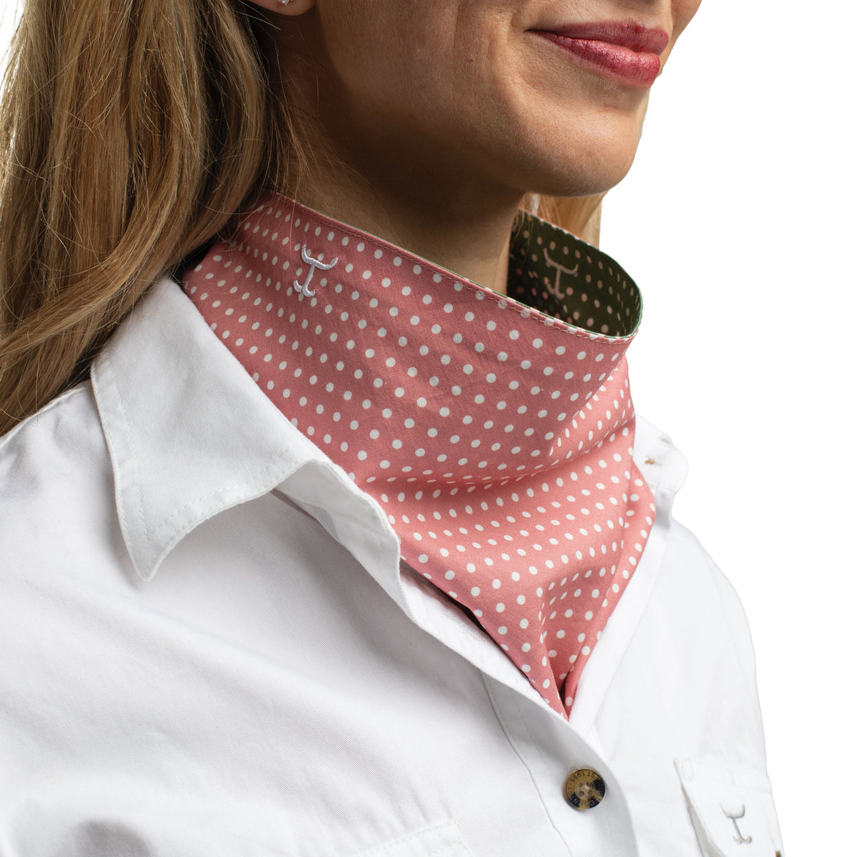 Person wearing a pink polka dot neck gaiter with a white shirt.