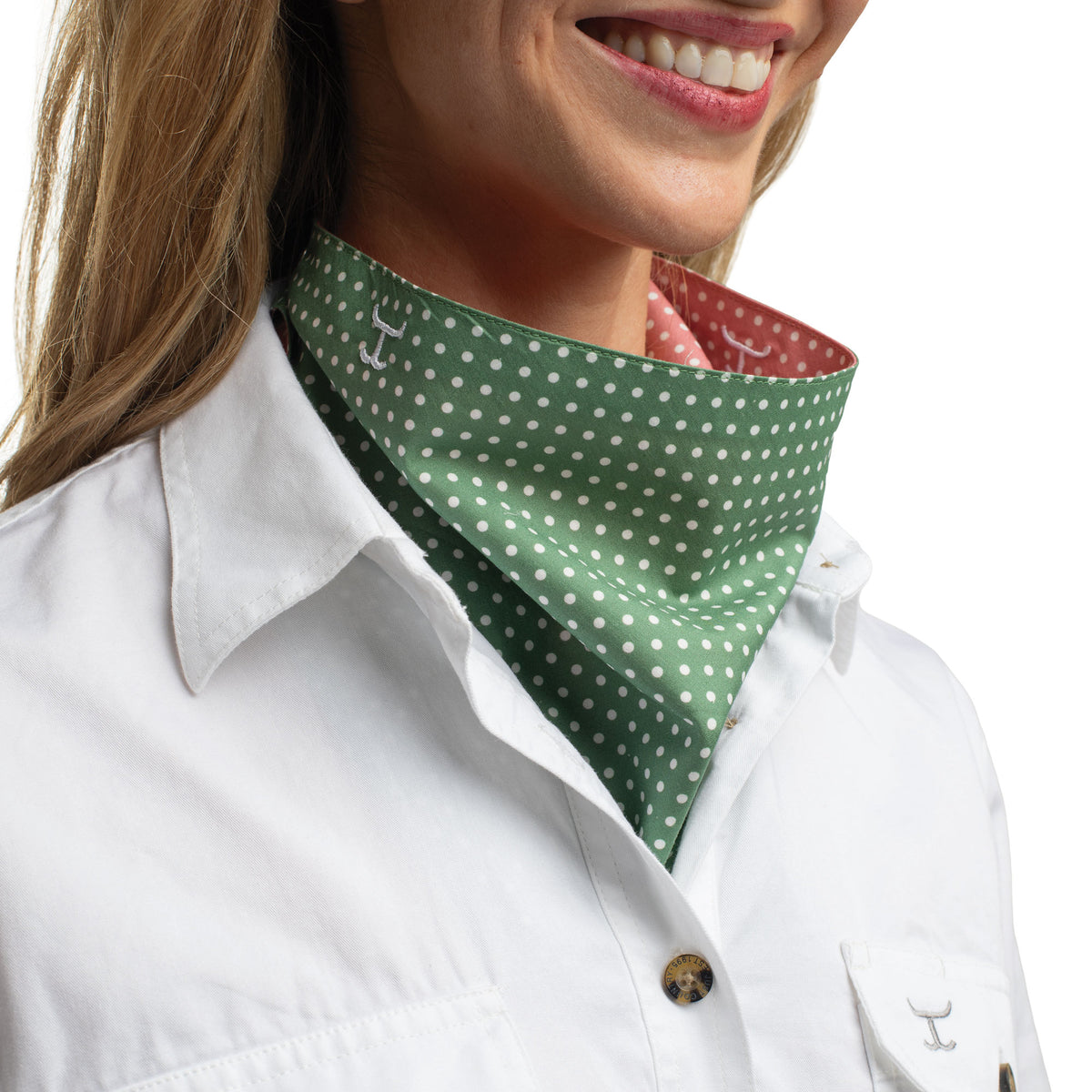 Person wearing a green polka dot bandana over a white shirt with a visible brand logo.