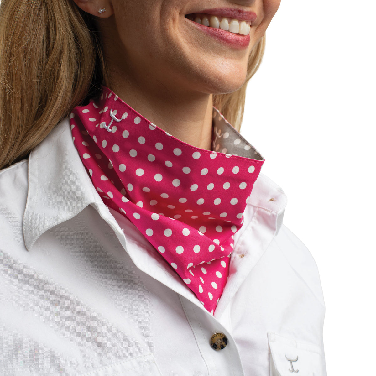 Woman wearing a pink polka dot scarf over a white shirt with a blurred background