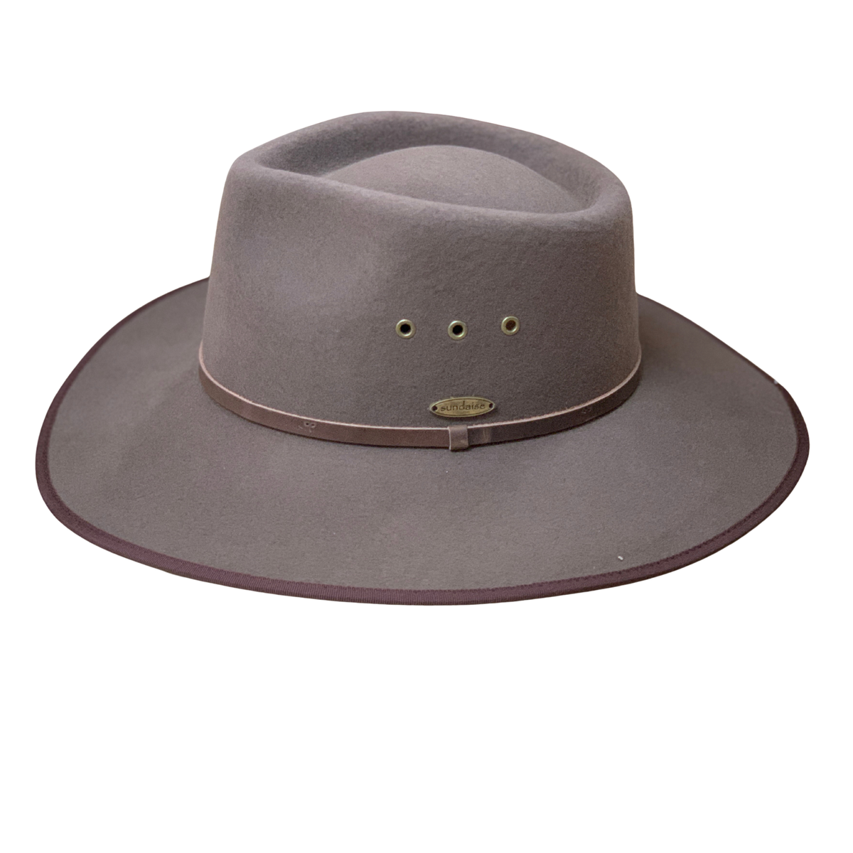 A wide-brimmed felt hat in a muted taupe-brown color, featuring a matching band with a small brass logo badge and ventilation eyelets on the crown, set against a plain white background.