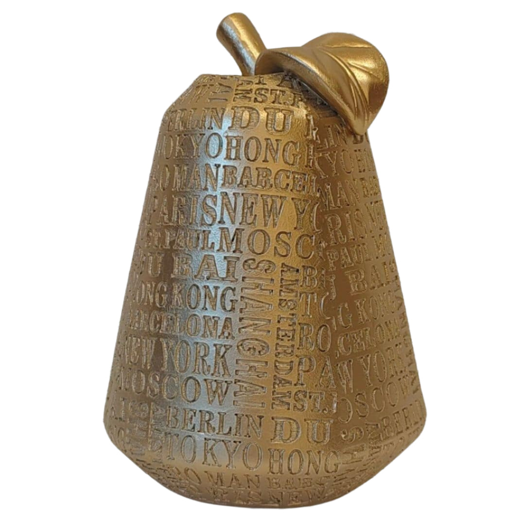 Golden Citi Pear. Decorative bell with embossed text against a white brick wall