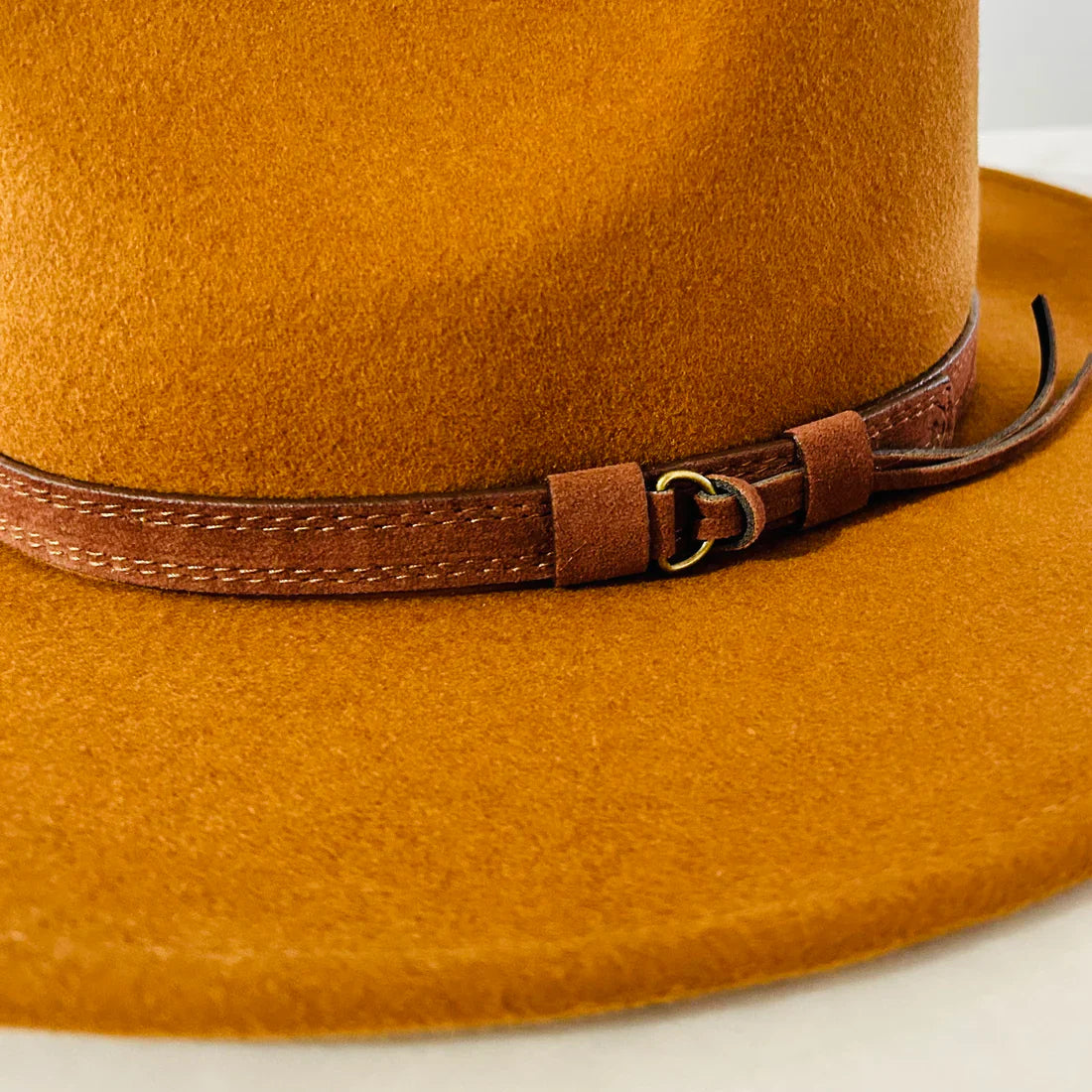 Sundaise Rhiannon Panama Hat. Close-up of a brown felt hat with a leather band on a white background