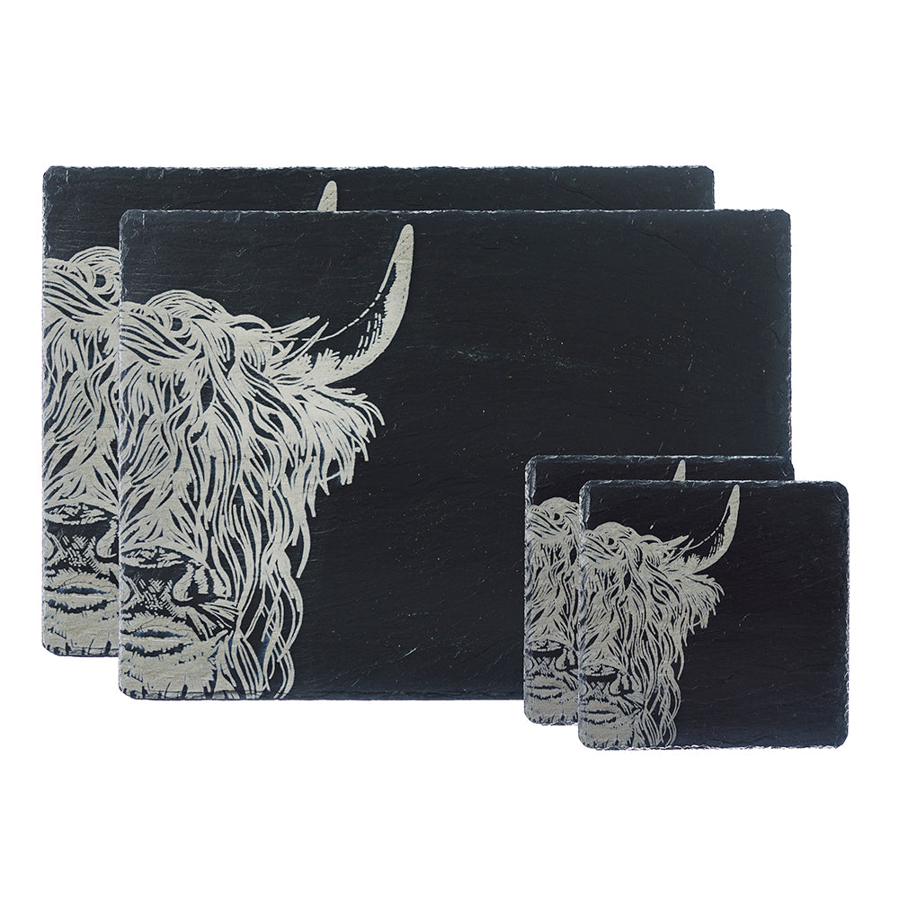A set of black slate placemats and coasters featuring a detailed white illustration of a Highland cow, arranged in a nested stack on a white background.