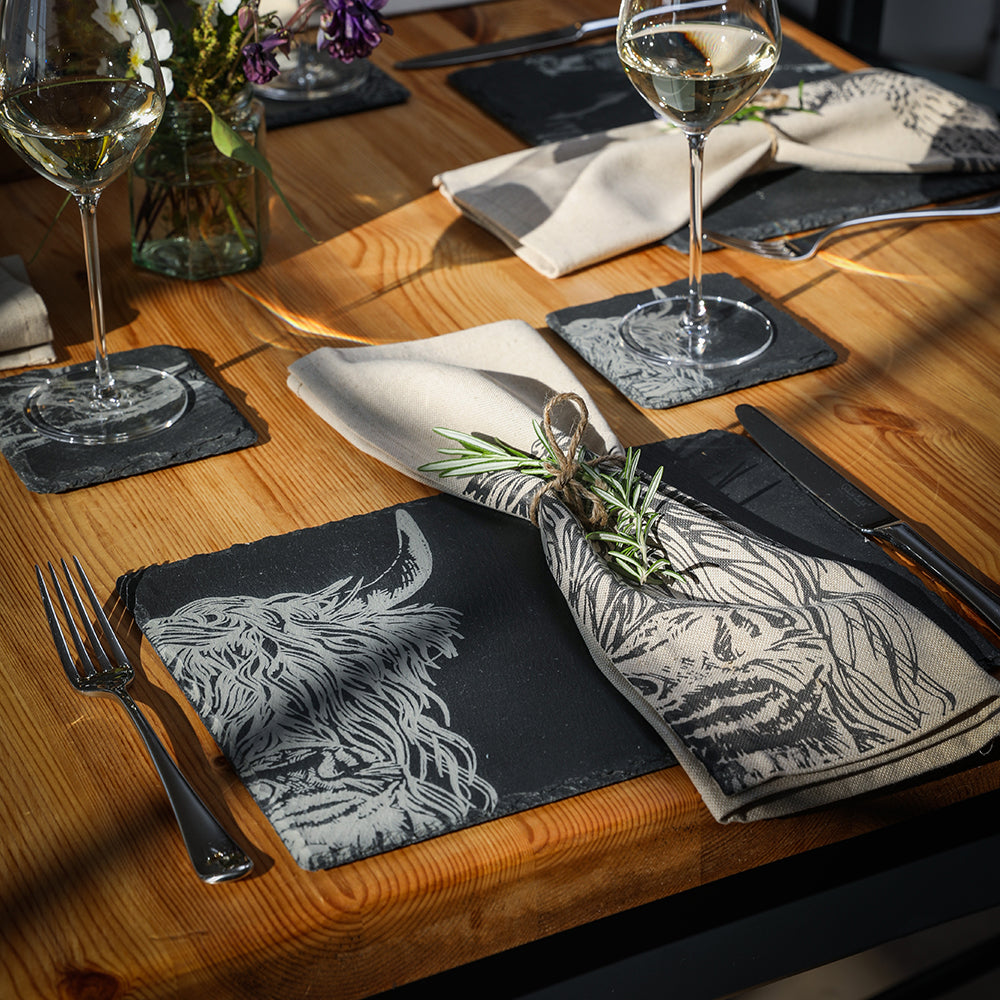 Dining table setting with wine glasses, napkins, and cutlery on a wooden surface.