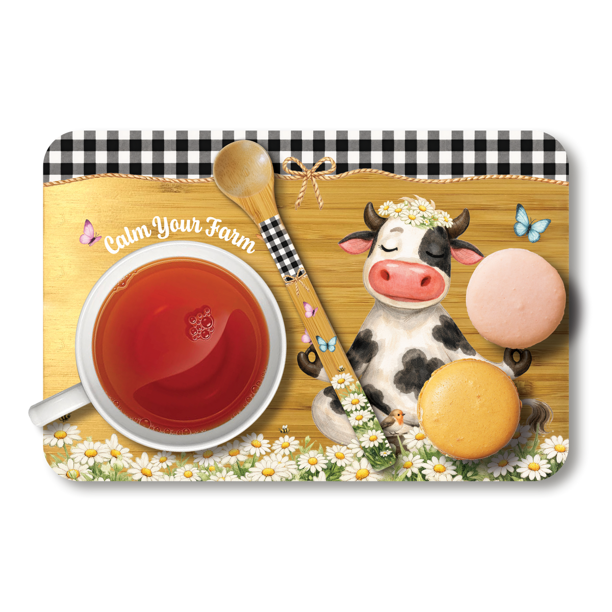 A rectangular placemat with rounded corners featuring a whimsical farm-themed tea party design. The design includes a black-and-white cow wearing a flower crown, a white teacup filled with red tea, a wooden spoon, two macarons, small butterflies, daisies, and a black-and-white gingham border.
