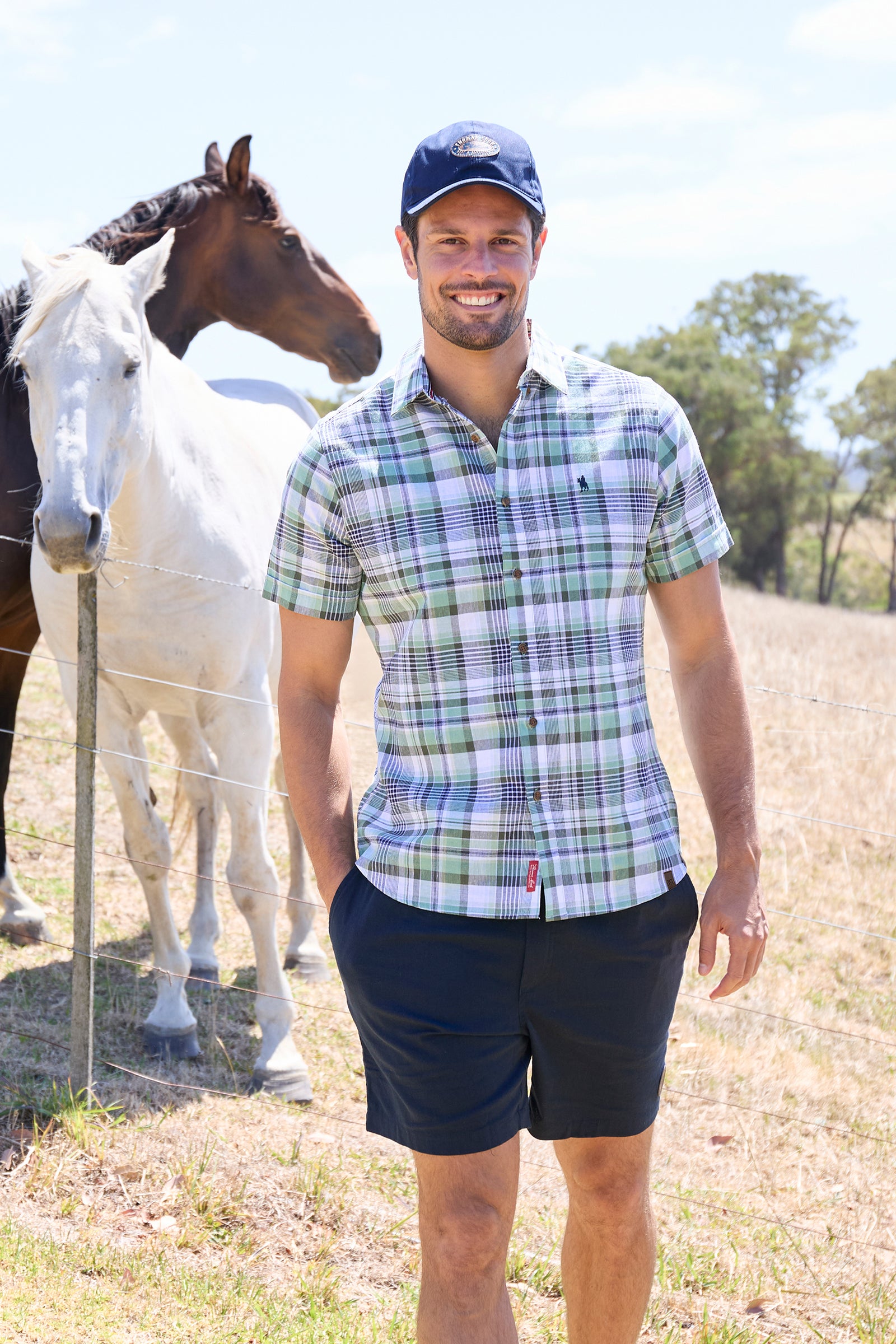 Man wearing a Thomas Cook Men's Gerry Linen S/S Shirt. Green and navy plaid shirt and navy pants on a white background