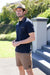 Man wearing a Thomas Cook Men's Ben Tailored S/S Polo. Navy polo shirt with a zipper pocket on a white background