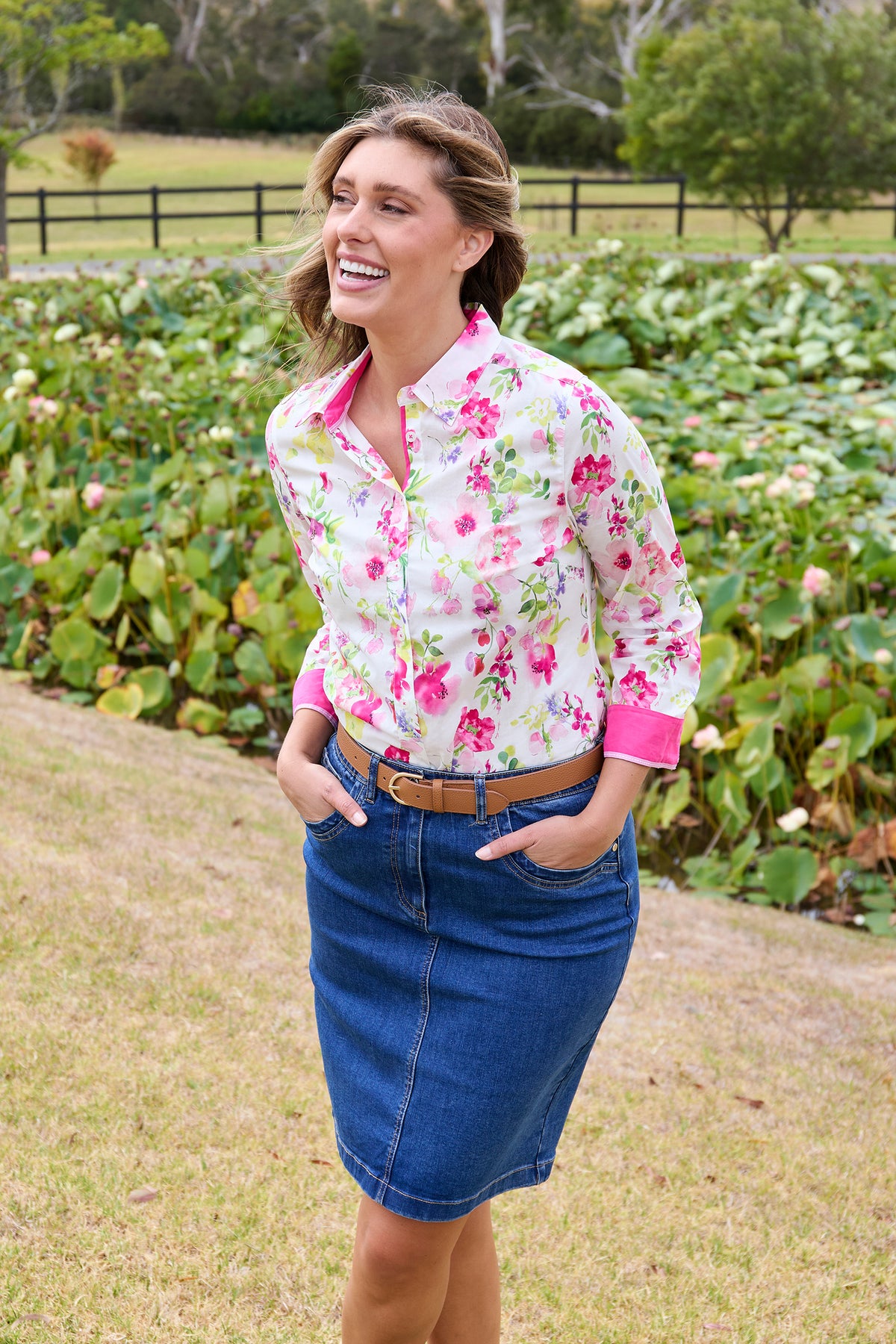 Thomas Cook Women's Mila L/S Western Shirt. Woman wearing a floral shirt and denim skirt standing in a garden.