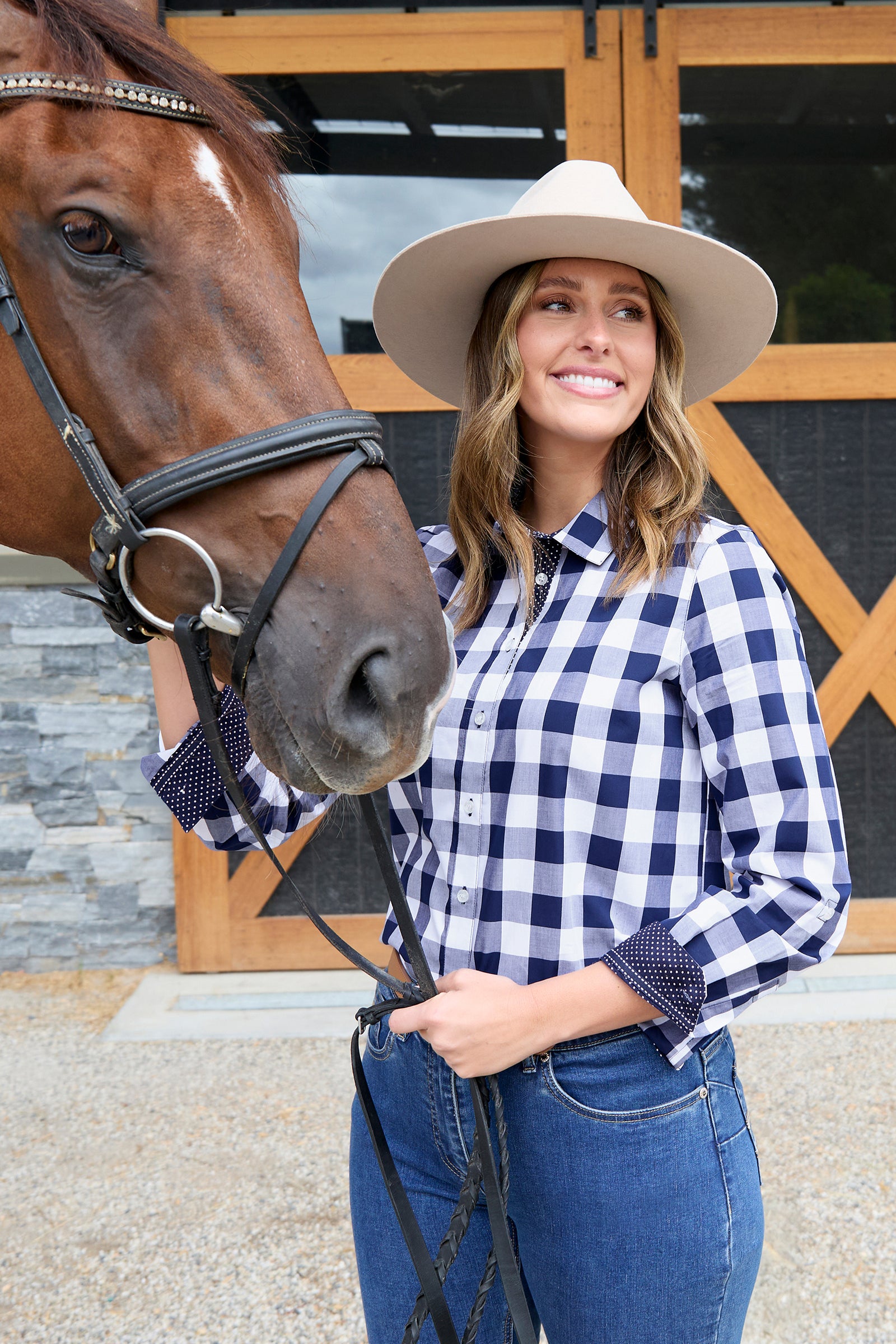 Woman wearing a Thomas Cook Women's Scarlet L/S Western Shirt. Bblue and white checkered shirt with jeans on a white background