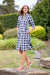 Thomas Cook Women's Bella Shirt Dress. Woman wearing a blue and white checkered dress in a garden setting
