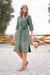 Thomas Cook Women's Sasha Shirt Dress. Woman wearing a green dress standing outdoors with a wooden fence and trees in the background.
