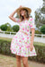 Thomas Cook Women's Flora S/S Dress. Woman wearing a floral dress and hat outdoors