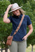 Thomas Cook Felicia Wallet Bag. Woman wearing a blue shirt, beige hat, and brown crossbody bag outdoors.