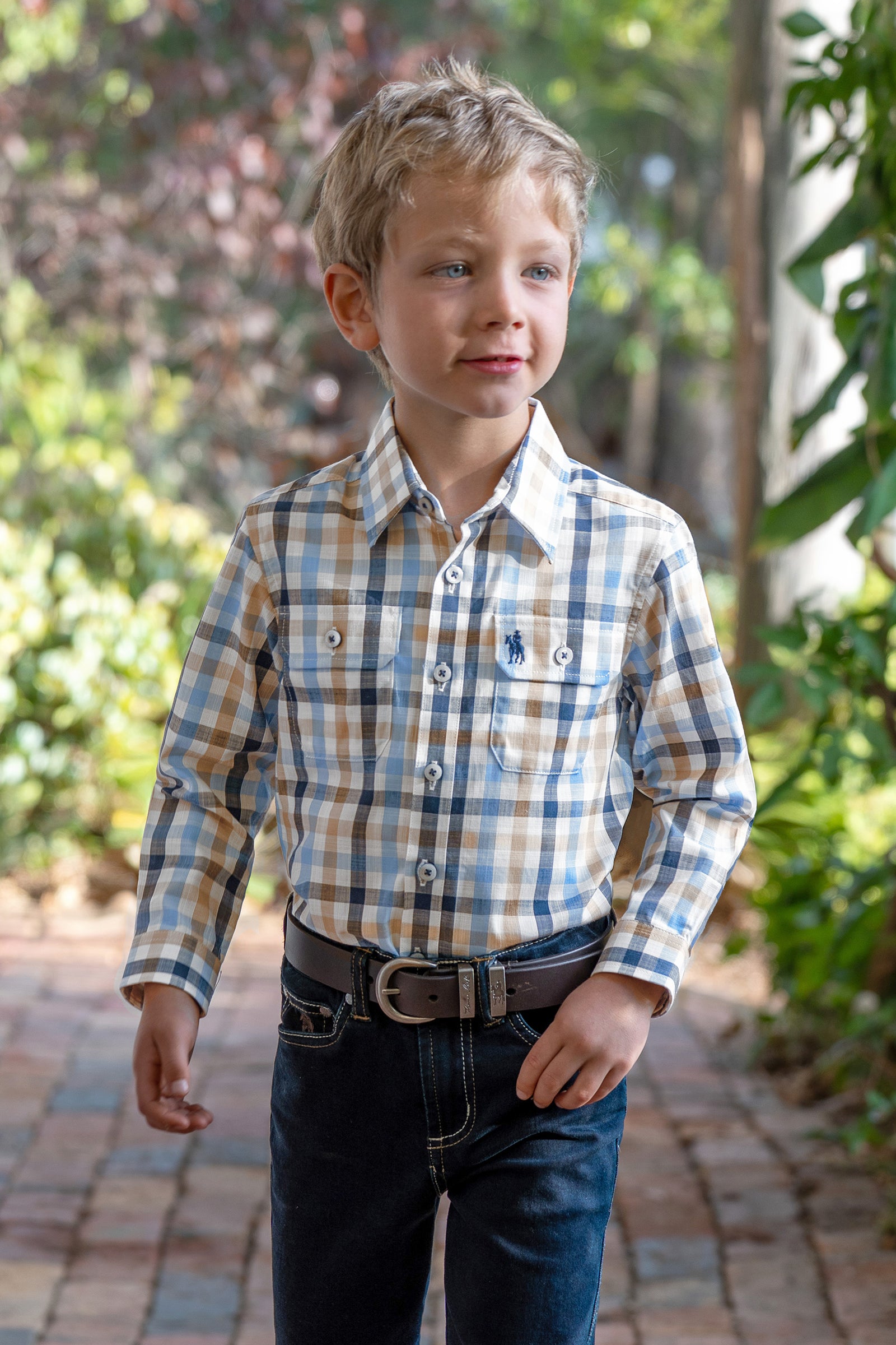 Young boy wearing a Thomas Cook Boy's Jesse L/S Western Shirt. Blue and beige checkered shirt with a belt on a white background