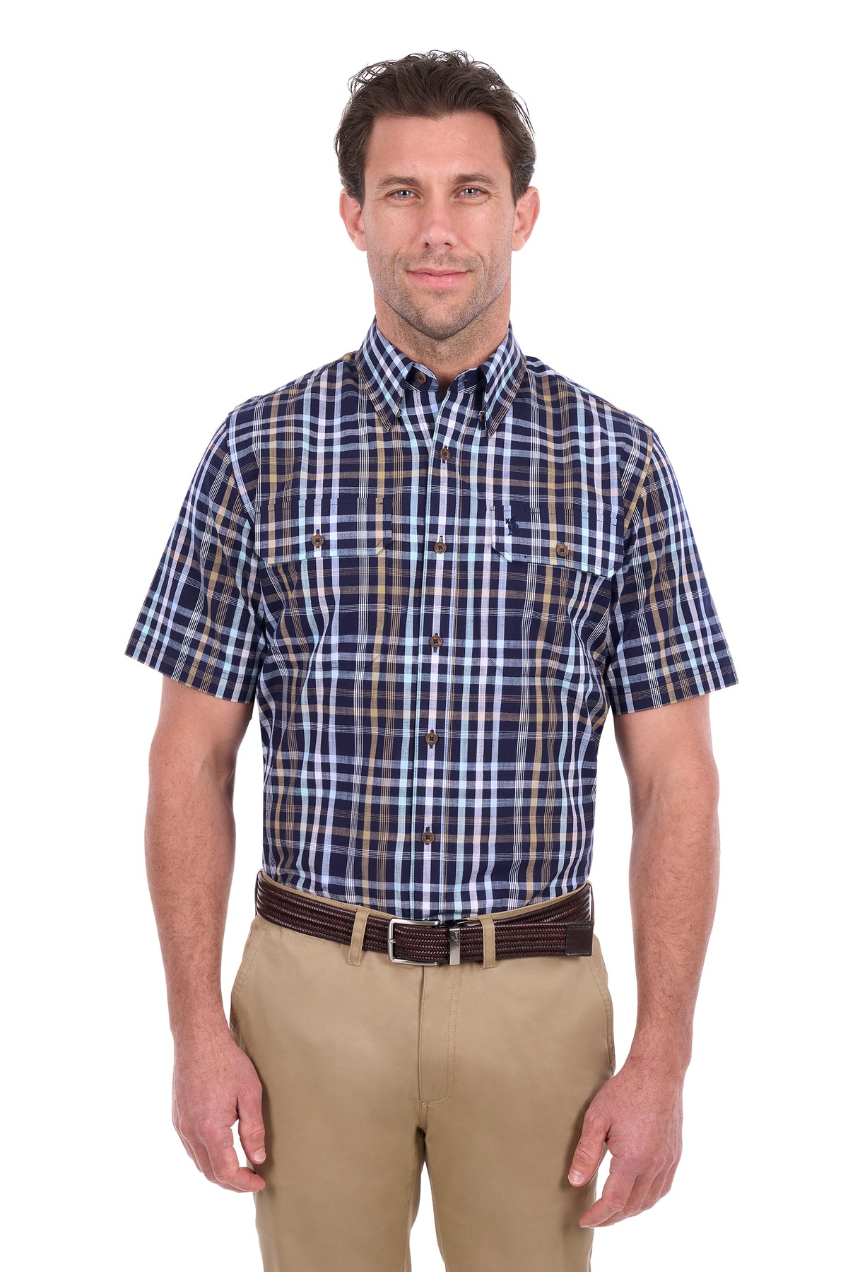 A man modeling a short-sleeve button-down plaid shirt in navy, blue, and brown, paired with khaki pants and a dark brown belt, against a plain white background.