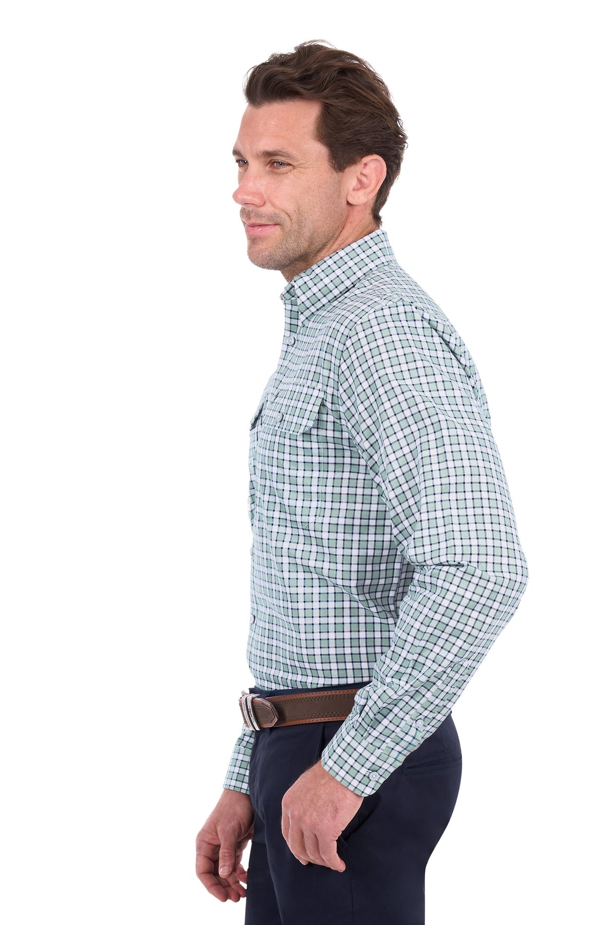 A man shown in profile wearing a long-sleeve button-down shirt with a green and white windowpane plaid pattern, paired with dark trousers and a brown belt, against a plain white background.