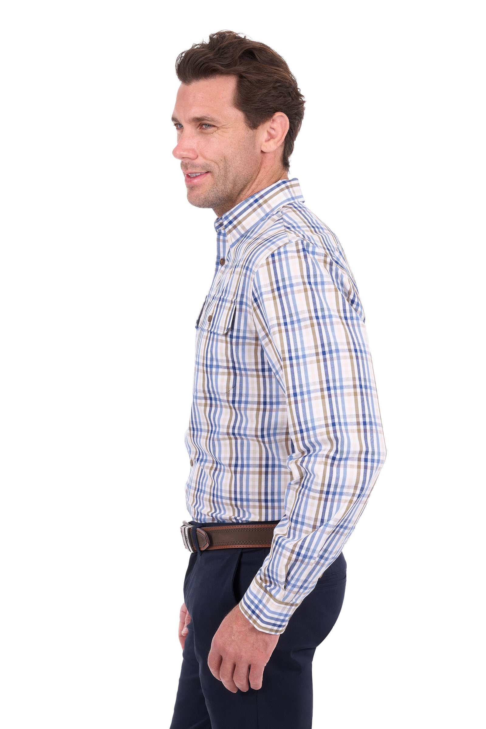 A man shown in profile wearing a long-sleeve button-down plaid shirt with blue, white, and tan stripes, paired with dark trousers and a brown belt, against a plain white background.