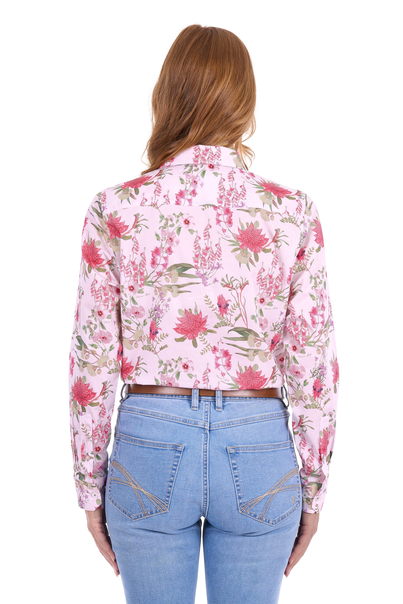 A woman viewed from the back wearing a light pink long-sleeve button-up shirt with a red and green floral print, paired with light blue jeans.