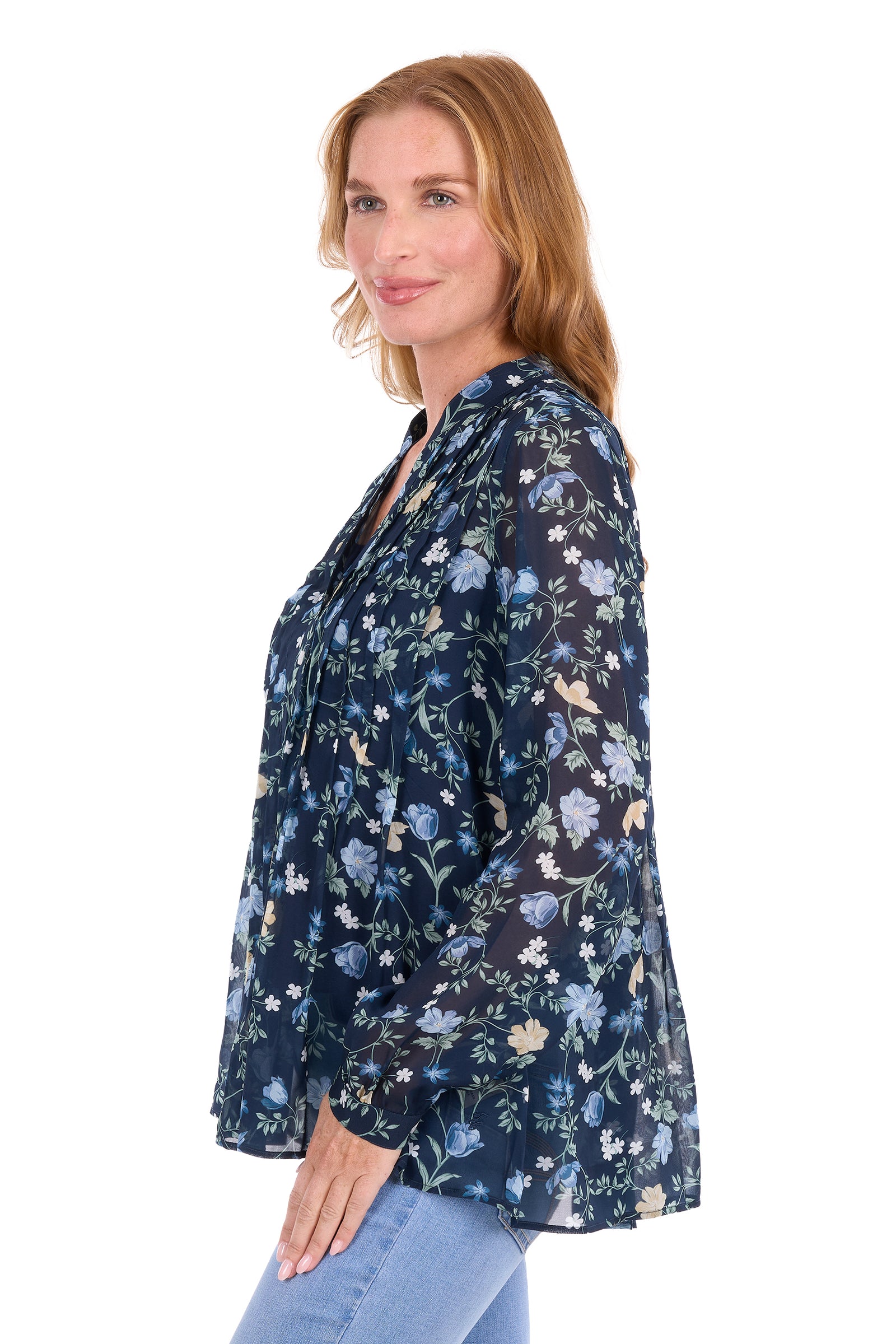 A woman wearing a navy blue long-sleeve blouse with a light blue, white, and beige floral pattern, paired with light blue jeans, shown from a side profile against a white background.