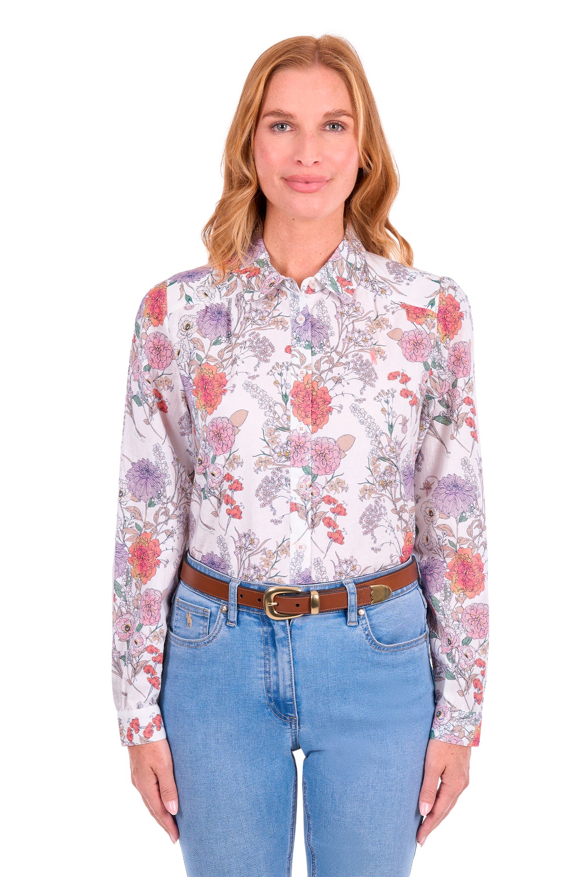 A woman modeling a long-sleeve button-up blouse with a multicolor floral and butterfly pattern on a white base, paired with blue jeans and a brown belt, against a plain white background.