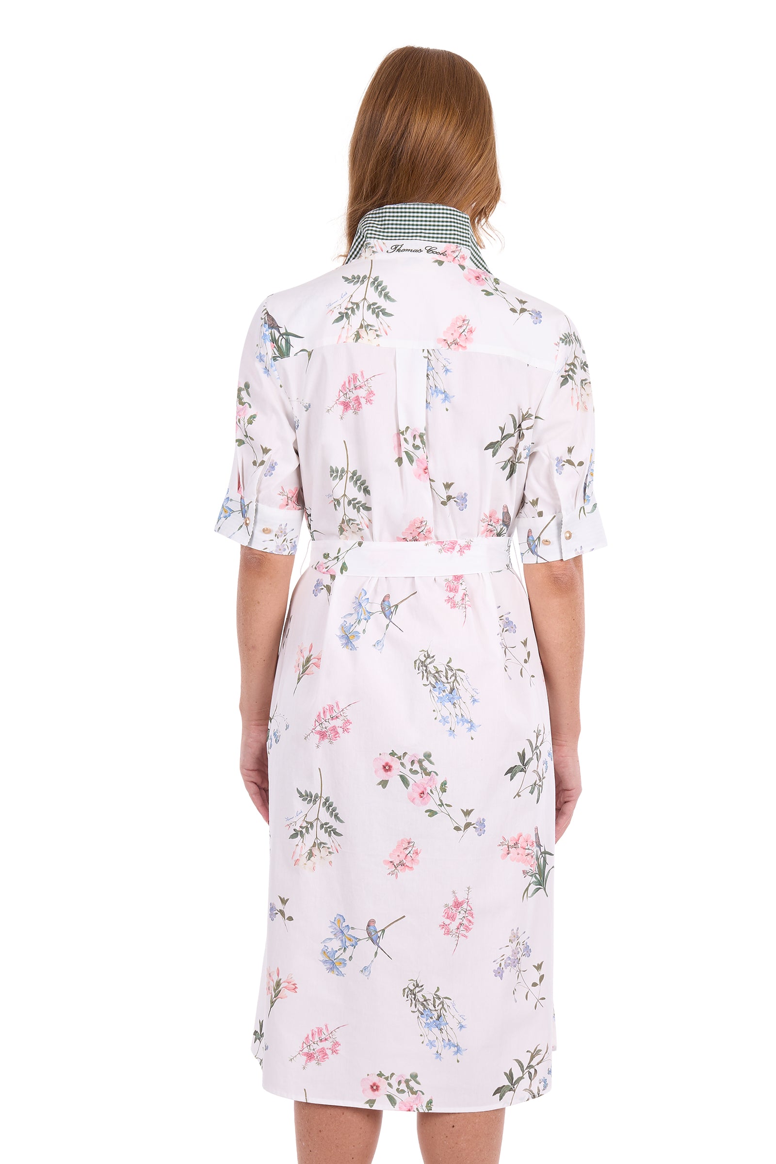 A woman viewed from the back wearing a short-sleeve collared shirt dress with a white base and a delicate pink, blue, and green floral print.