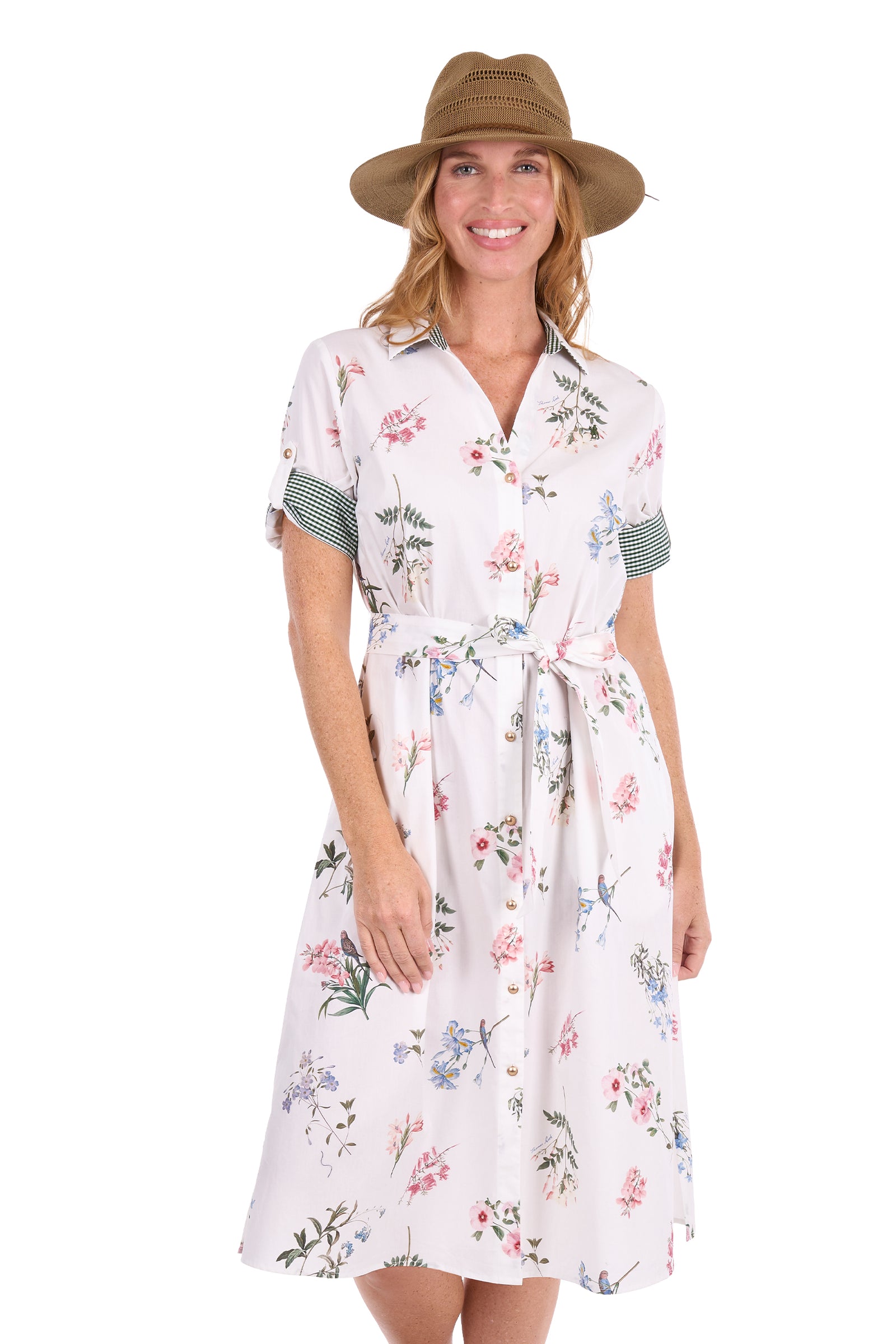 A woman modeling a white short-sleeve floral shirt dress with green striped sleeve cuffs, a matching tie belt, and a brown wide-brim hat against a plain white background.