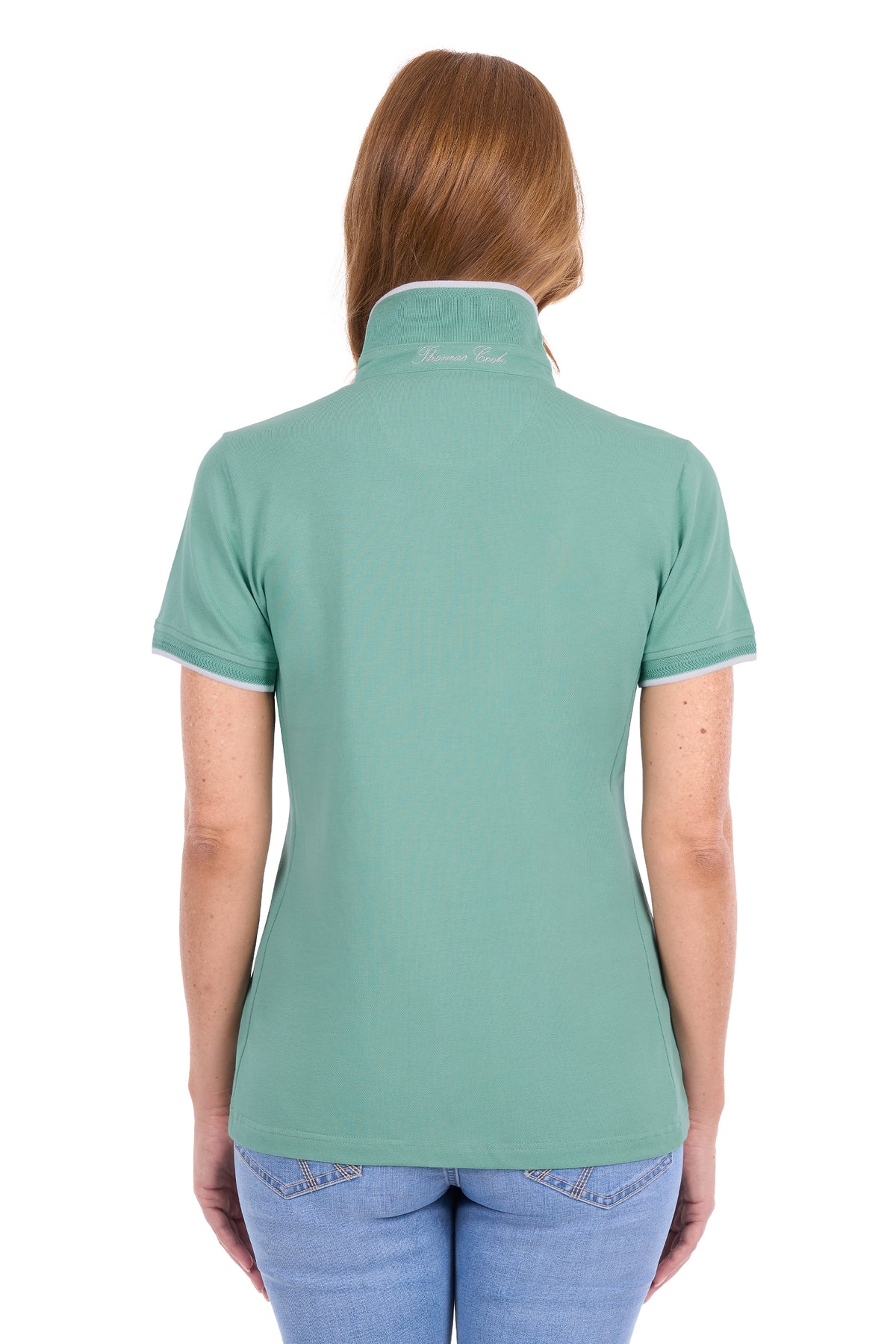 A woman viewed from the back wearing a sage green short-sleeve polo shirt with white trim on the collar and sleeve cuffs, paired with blue jeans against a plain white background.