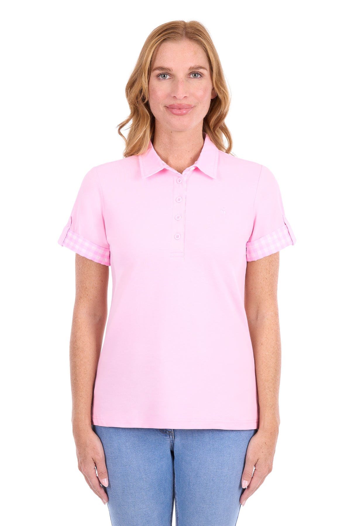 A woman modeling a light pink short-sleeve polo shirt with blue jeans against a plain white background.