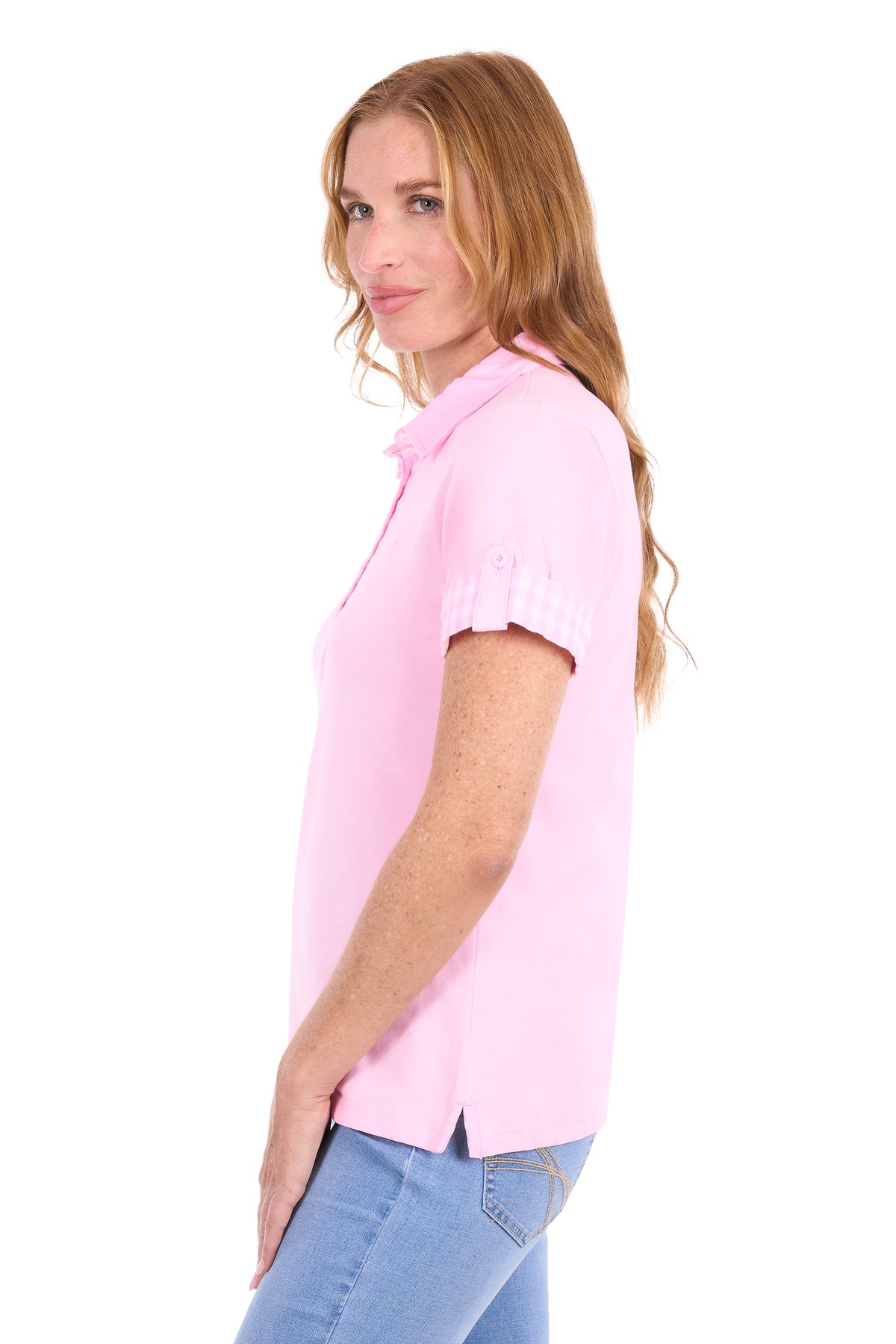 A woman with long light brown hair is shown from a side-back angle wearing a light pink short-sleeve polo shirt and light blue jeans against a plain white background.