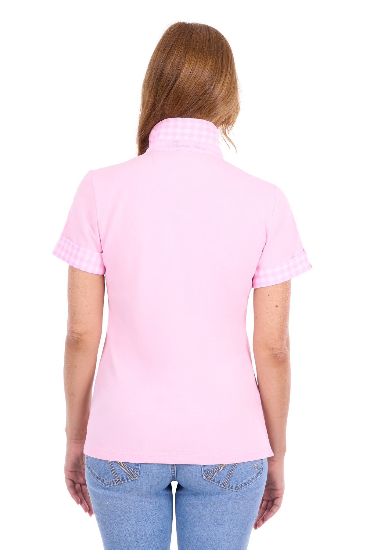 A woman viewed from the back wearing a light pink short-sleeve polo shirt with a subtle gingham pattern on the collar and sleeve cuffs, paired with blue jeans against a plain white background.