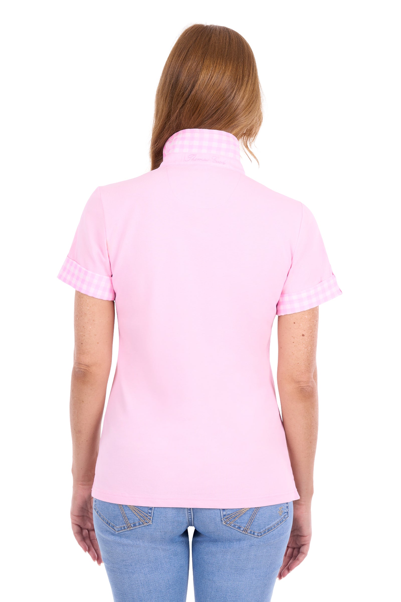A woman viewed from the back wearing a light pink short-sleeve polo shirt with a subtle gingham pattern on the collar and sleeve cuffs, paired with blue jeans against a plain white background.