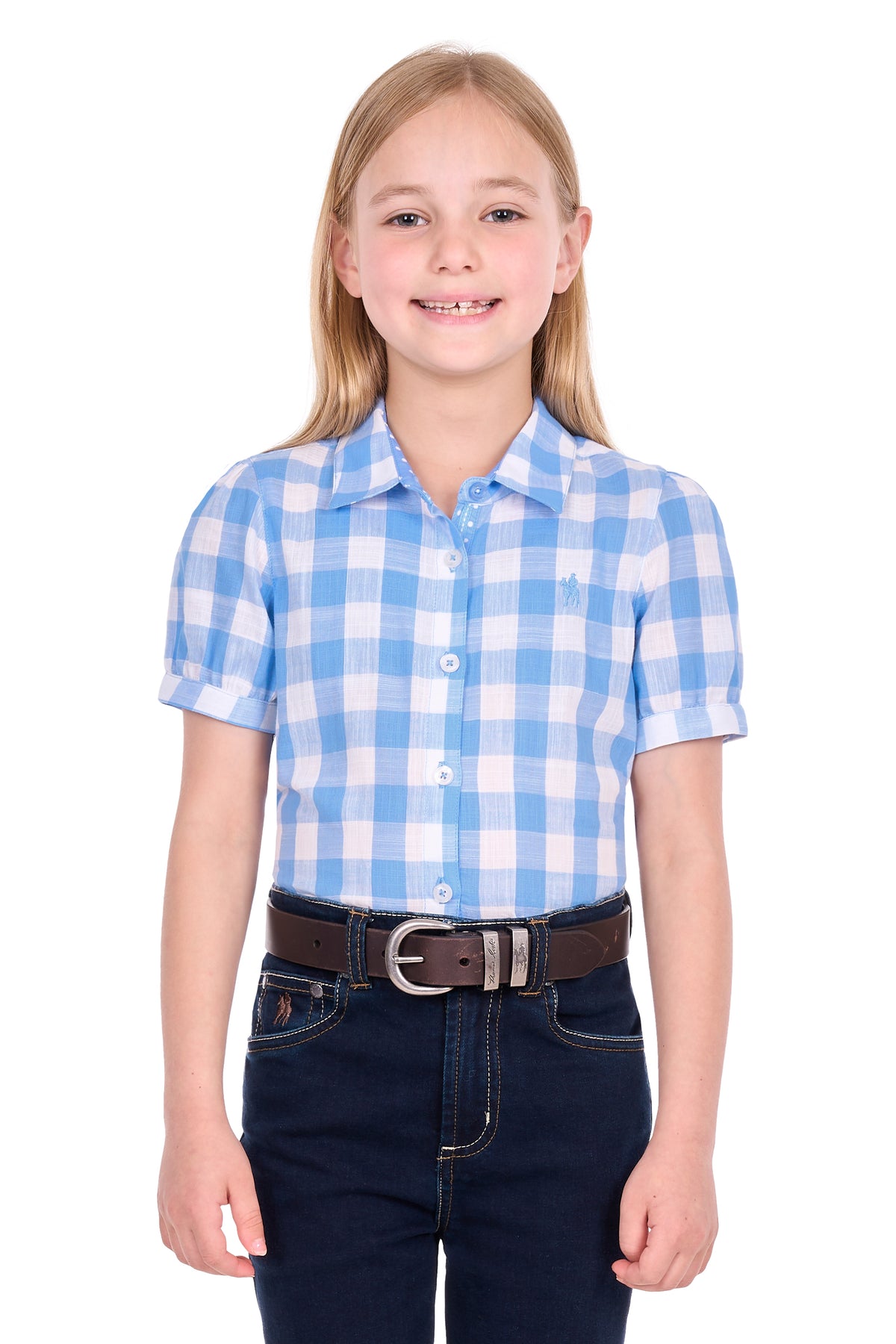 A young girl with blonde hair wearing a light blue and white gingham short-sleeve button-up shirt, dark blue jeans, and a brown belt, standing against a plain white background.
