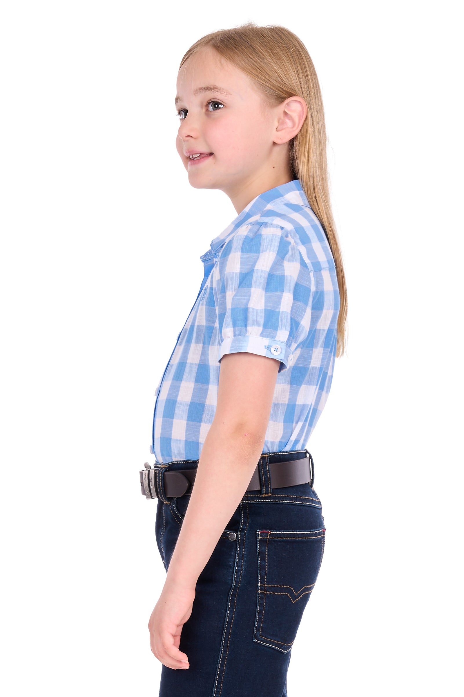 A young girl with blonde hair tied back, shown in profile wearing a light blue and white gingham short-sleeve button-up shirt, dark blue jeans, and a black belt, against a plain white background.
