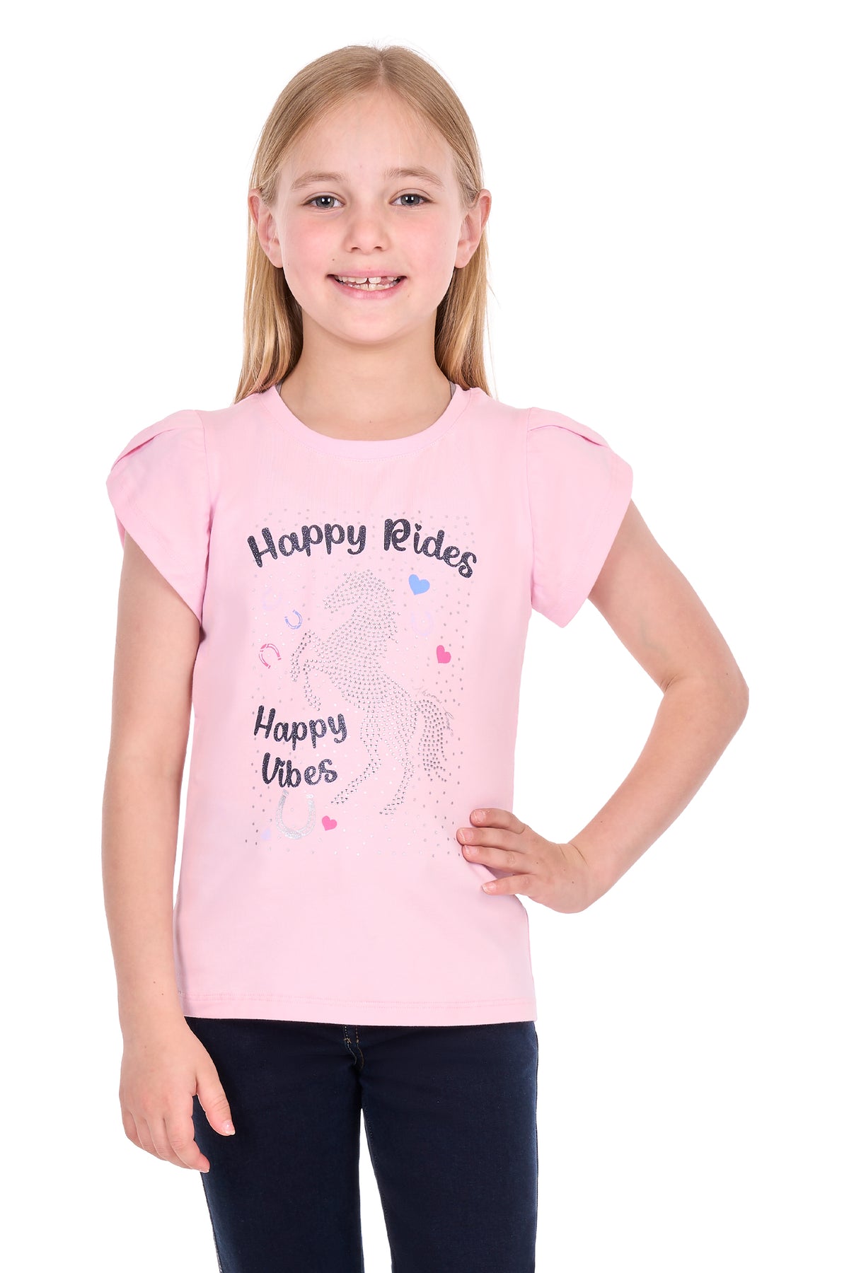 A young girl with blonde hair wearing a light pink short-sleeve t-shirt with a 'Happy Rides Happy Vibes' graphic on the front, paired with dark pants, against a plain white background.