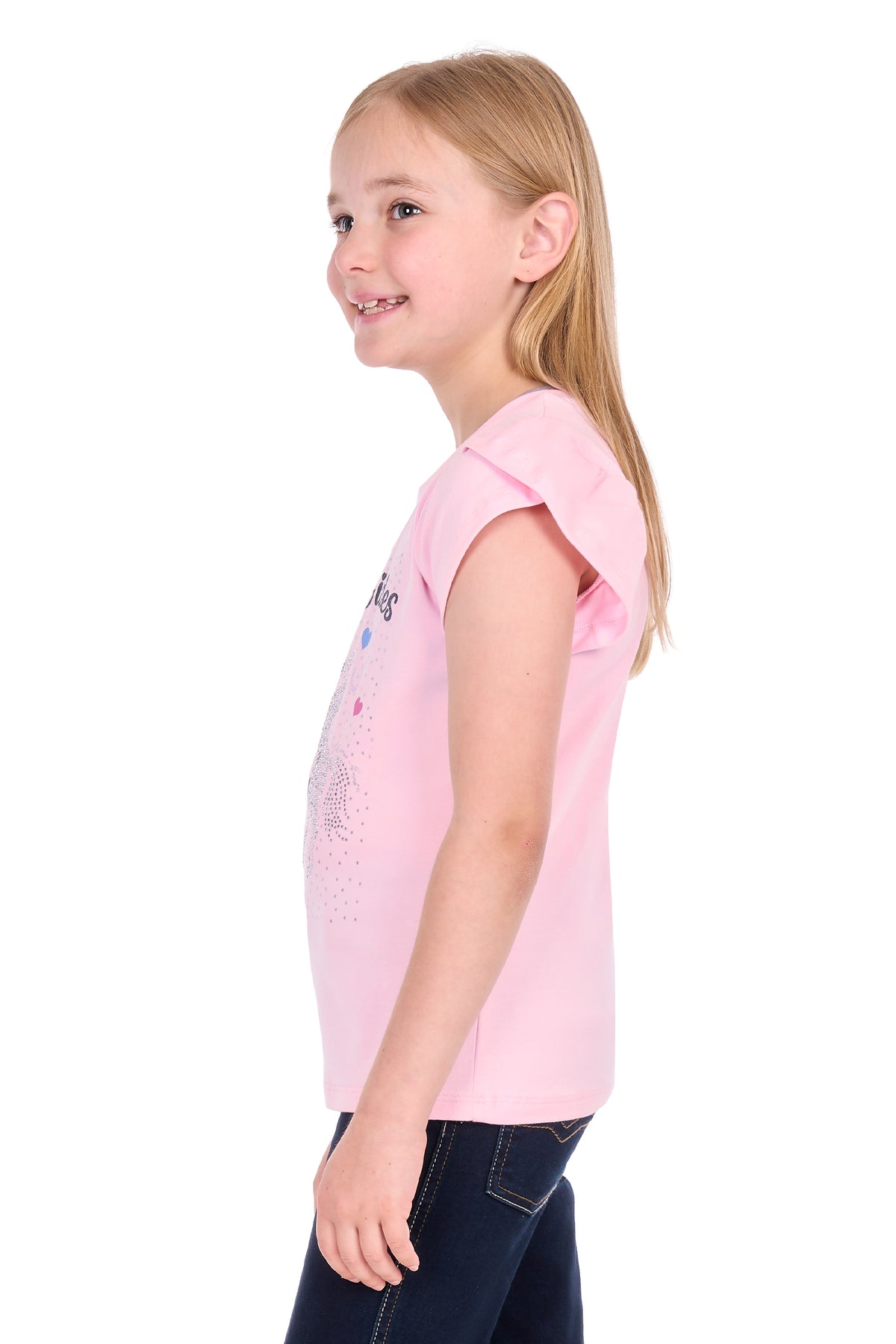 A young girl with blonde hair is shown in profile wearing a light pink sleeveless top with a subtle graphic on the front, paired with dark blue jeans, against a plain white background.