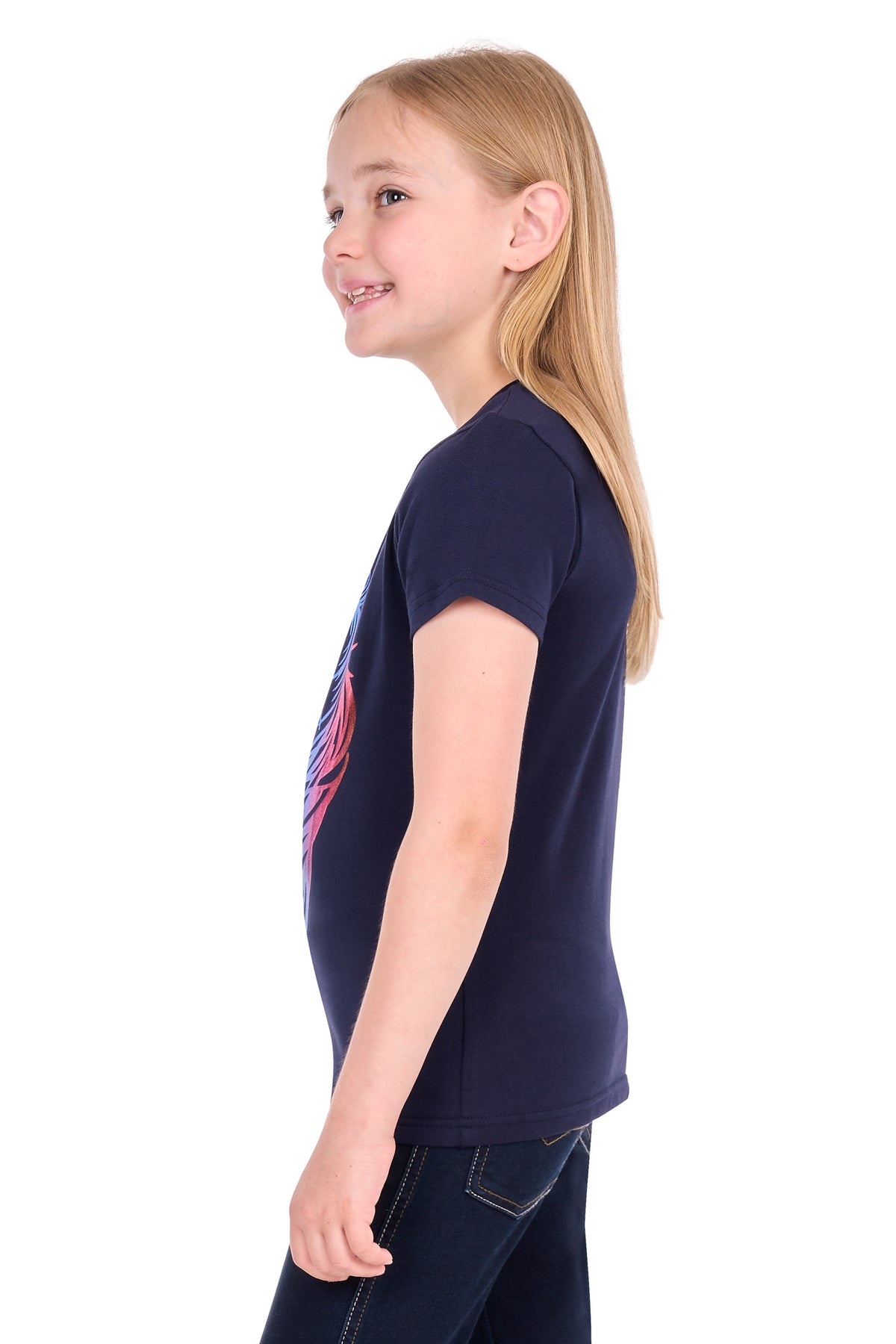 A young girl with long blonde hair is shown in profile wearing a navy blue short-sleeve t-shirt with a pink graphic on the front, paired with dark blue jeans, against a solid white background.