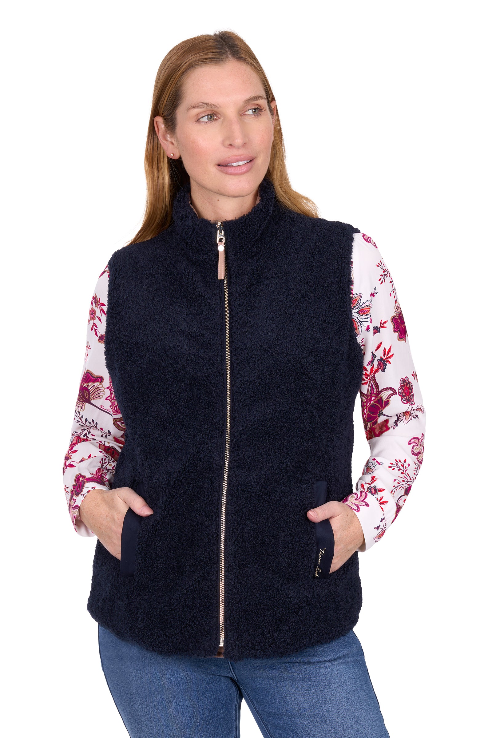 Woman wearing a beige quilted vest over a floral shirt on a white background