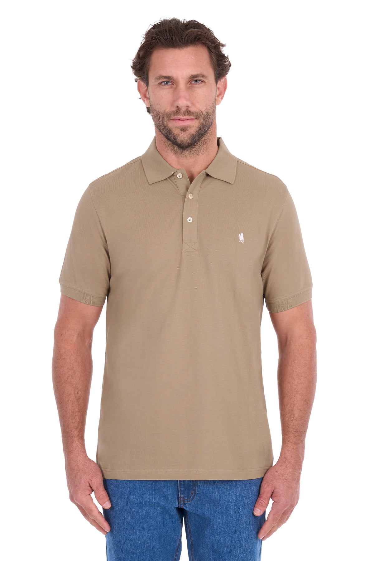 A man wearing a beige short-sleeve polo shirt with a small white embroidered logo on the chest, paired with blue jeans, against a plain white background.