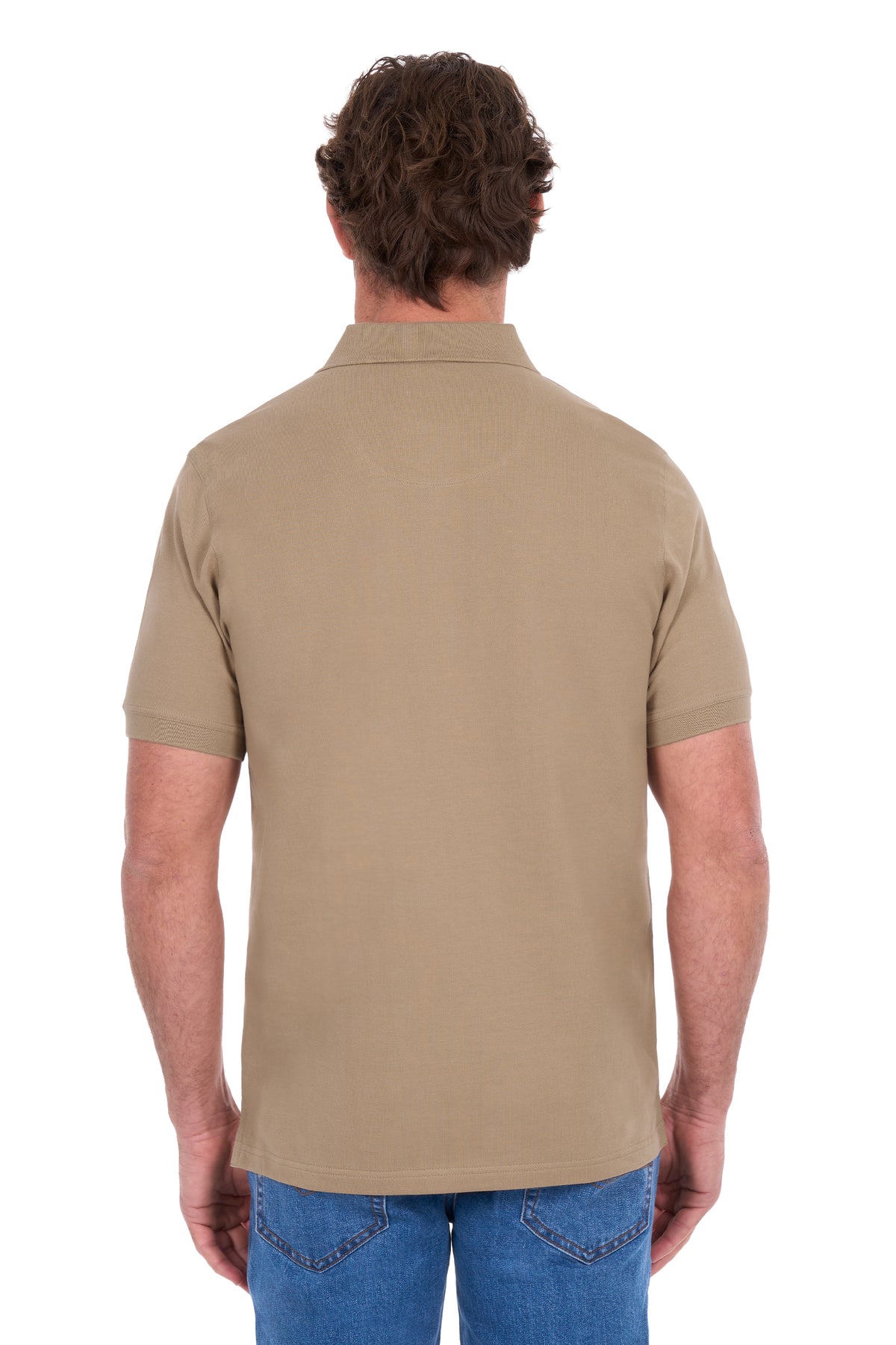 A man viewed from the back wearing a short-sleeve polo shirt in a solid tan color, paired with blue jeans, against a plain white background.