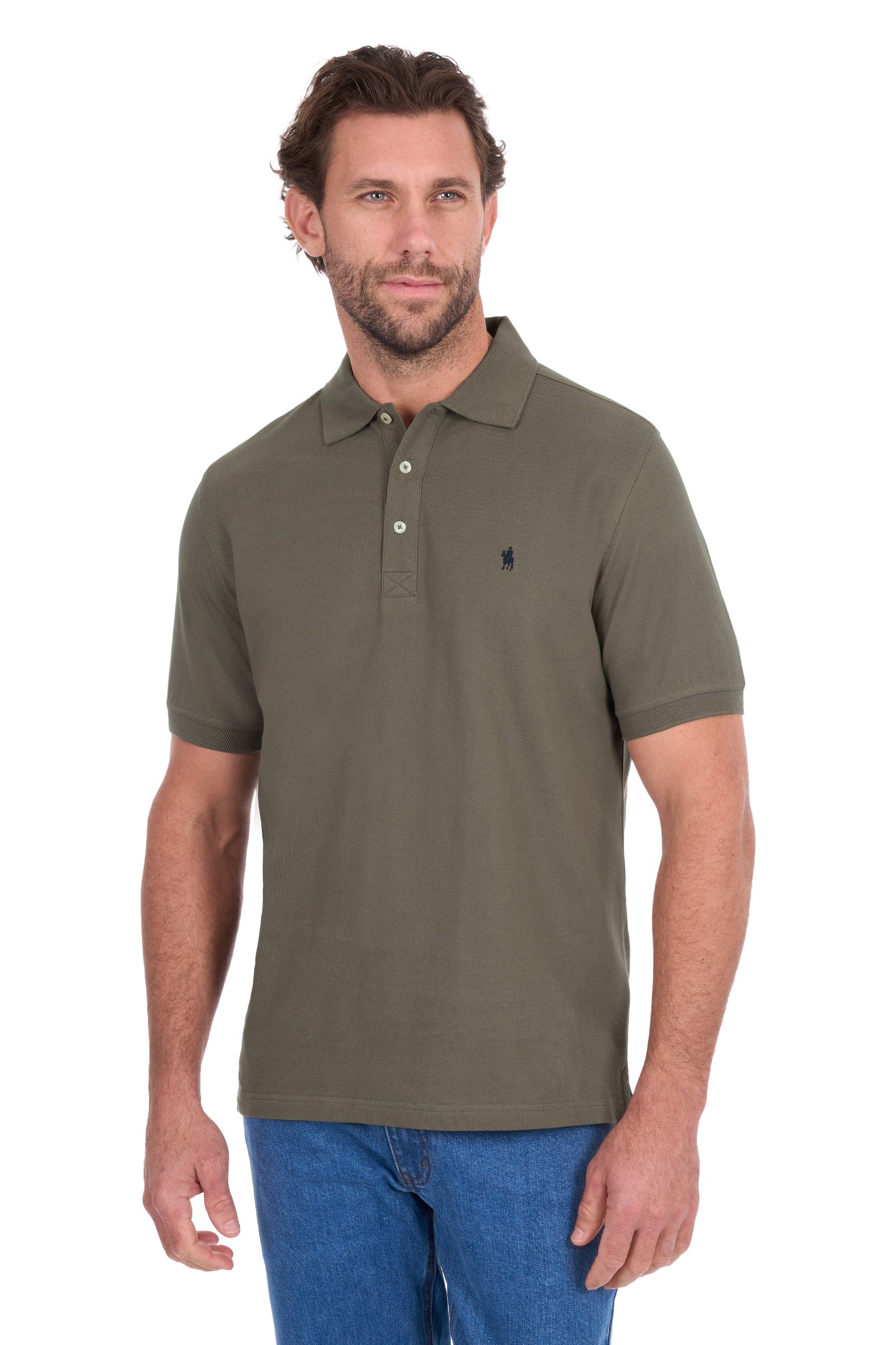 A man wearing an olive green short-sleeve polo shirt with a small navy embroidered logo on the left chest, paired with blue jeans, against a plain white background.