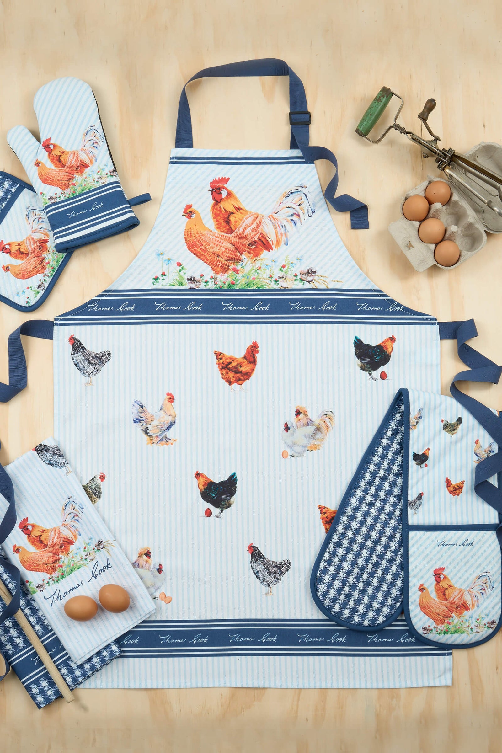 A Thomas Cook chicken-themed apron displayed on a mannequin. The apron has a white base with blue stripes and is adorned with illustrations of chickens in various colors.