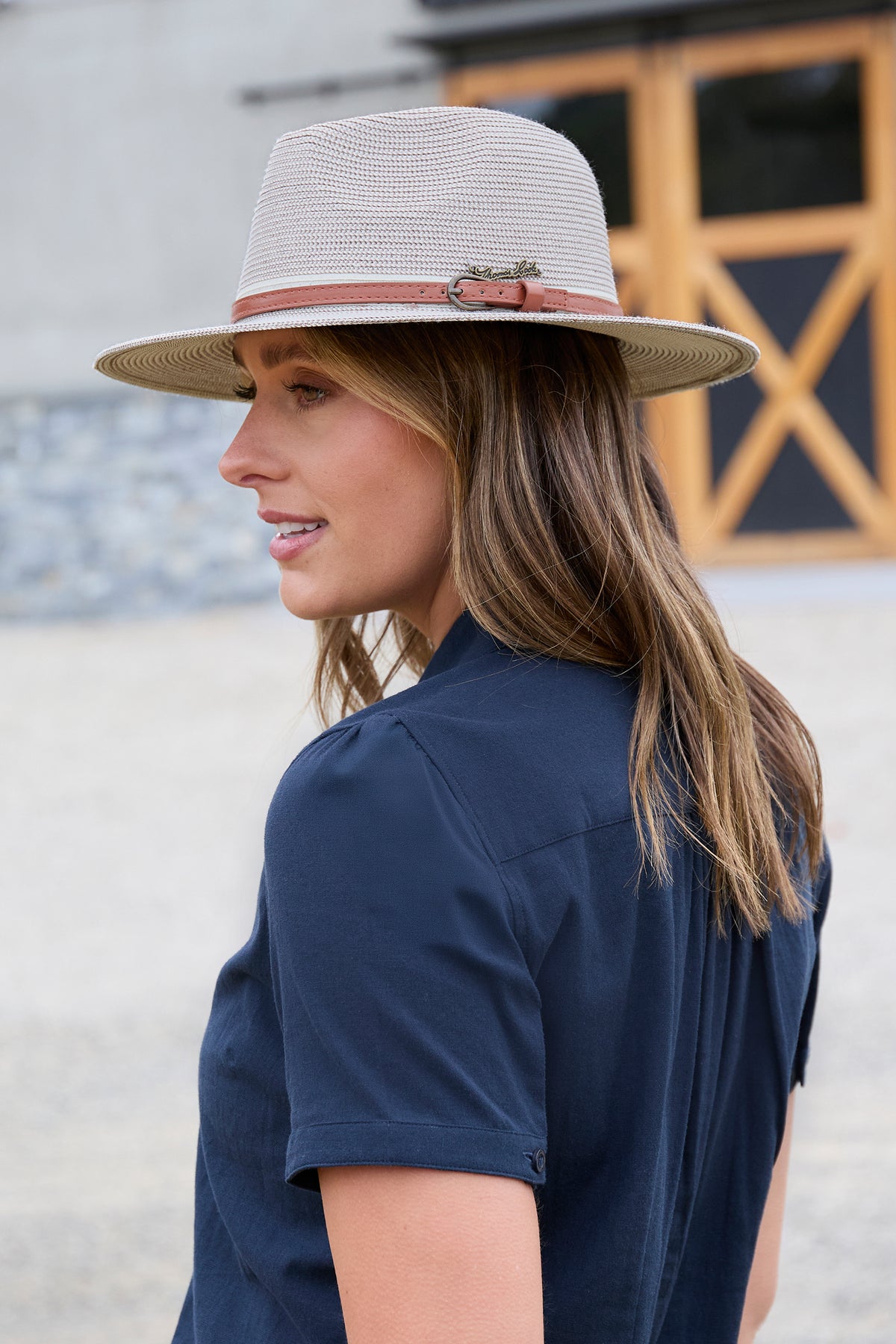Thomas Cook Hampton Hat. Woman wearing a straw hat with a brown band outdoors