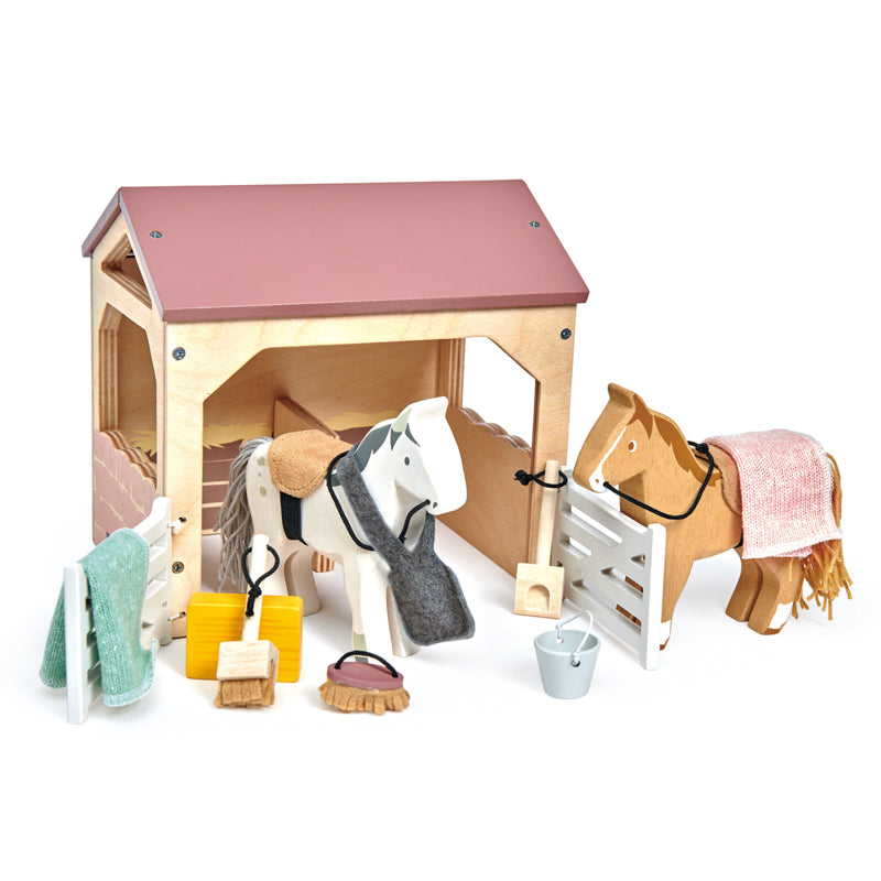 Kaleidoscope The Stables. Toy stable with two horses, grooming tools, and a white background