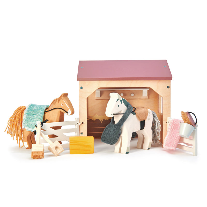 Kaleidoscope The Stables. Toy stable with two horses, grooming tools, and a white background