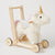 Jiggle & Giggle Unicorn Walker. Plush unicorn toy with a wooden cart on a light background