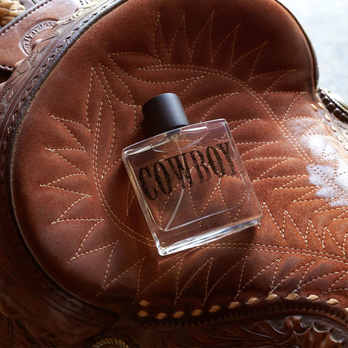 Cowboy-themed perfume bottle on a brown leather surface